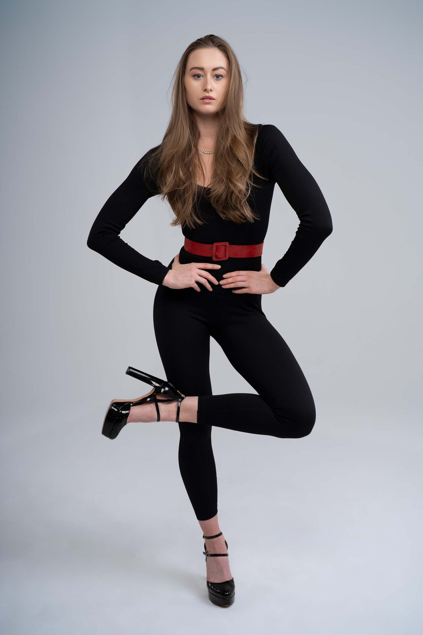 Close portrait of a model in a black top with hand near her face, studio photography