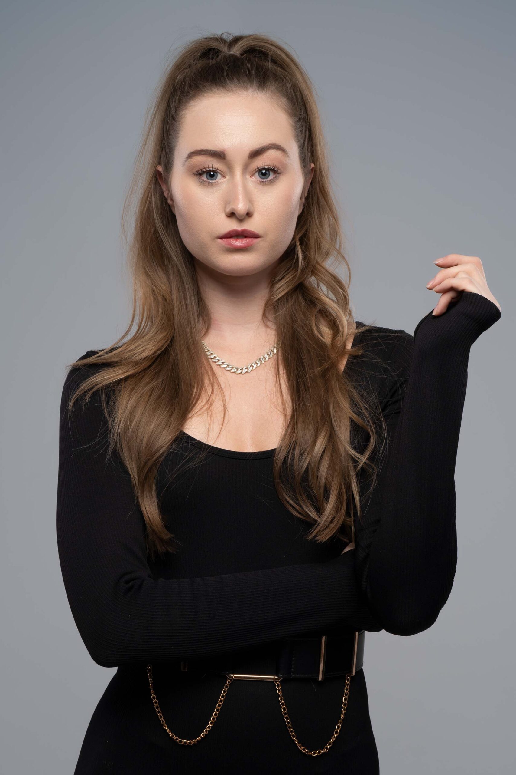 Close portrait of a model with hand near her chin, black top, studio photography
