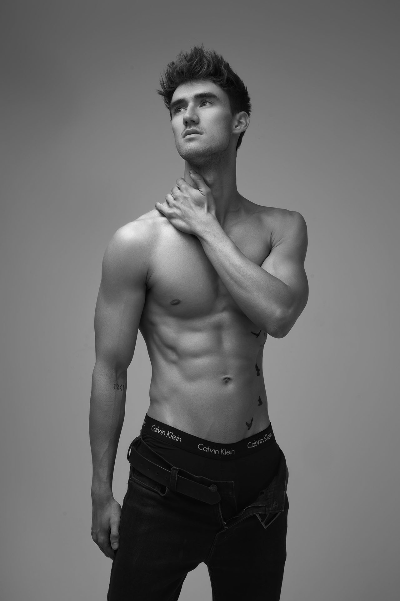 Shirtless male model with hand near his head, dramatic studio lighting