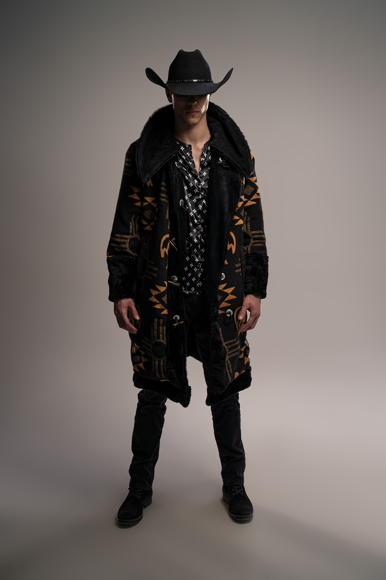 Man in a cowboy hat and patterned black coat, standing western-themed editorial portrait