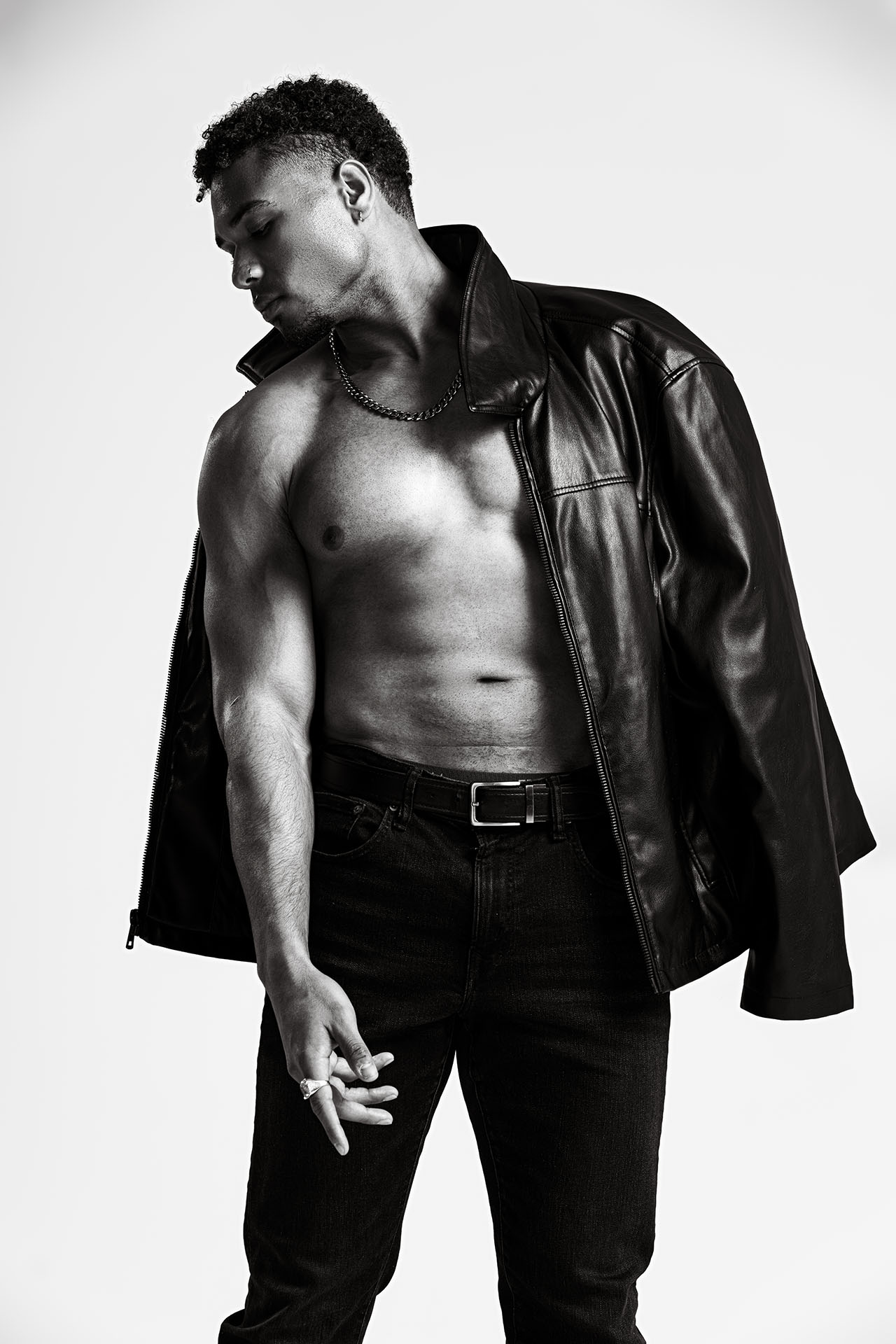 Black-and-white portrait of a man in an open shirt with a statement necklace