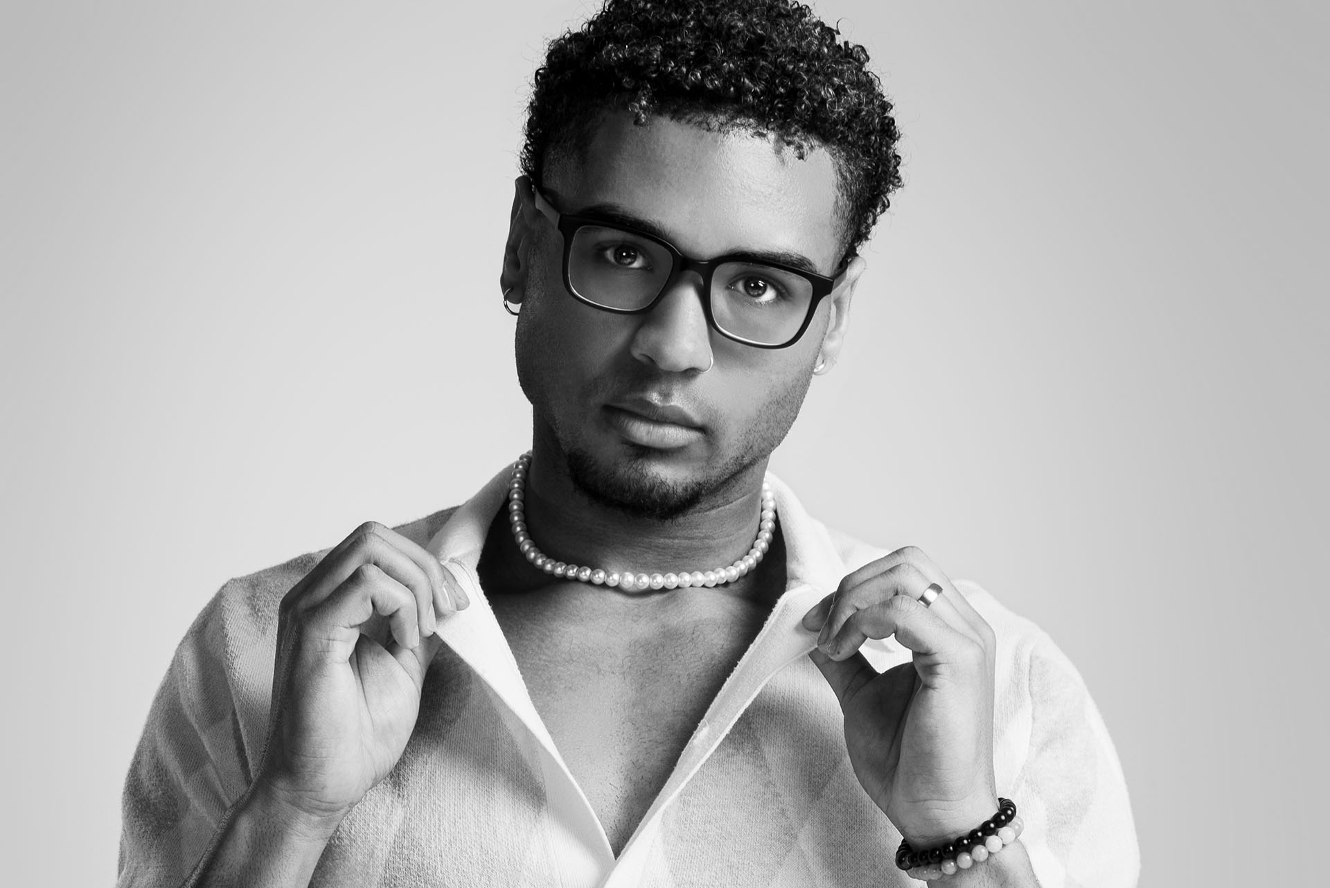 Man in a crouched dynamic pose wearing a plaid shirt and sunglasses, studio photography