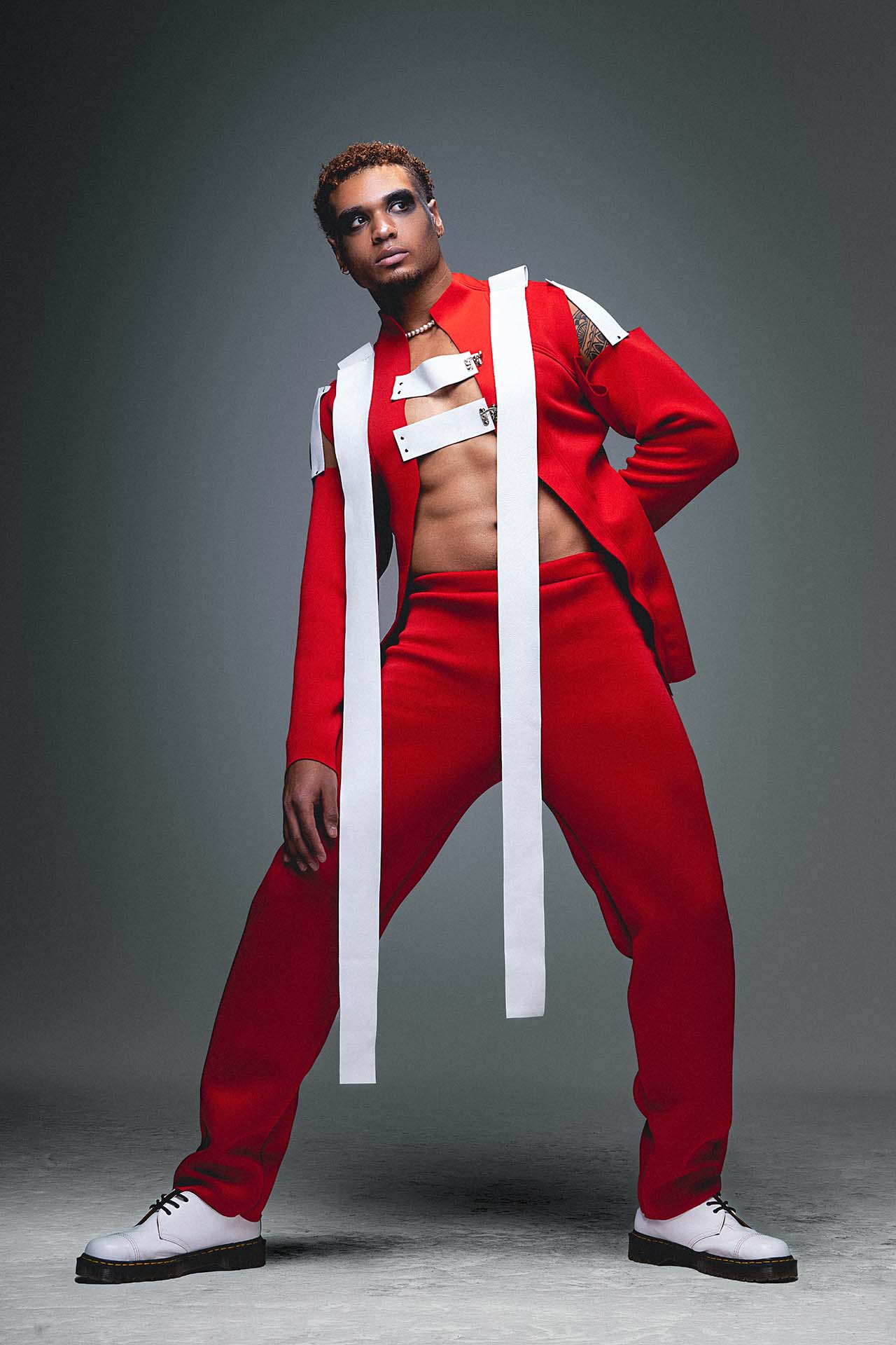 Model in a red top and white skirt with white boots, dynamic studio fashion photography