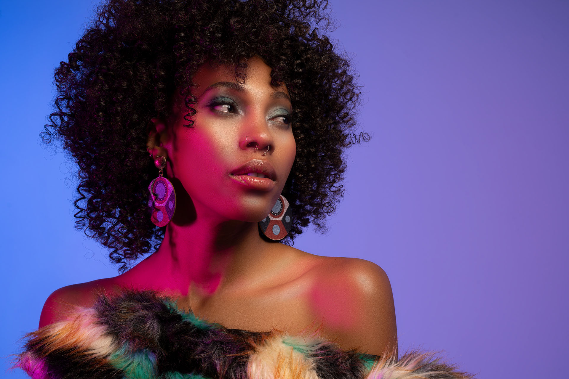 Model in a flowing red dress in a dynamic pose under purple studio lighting