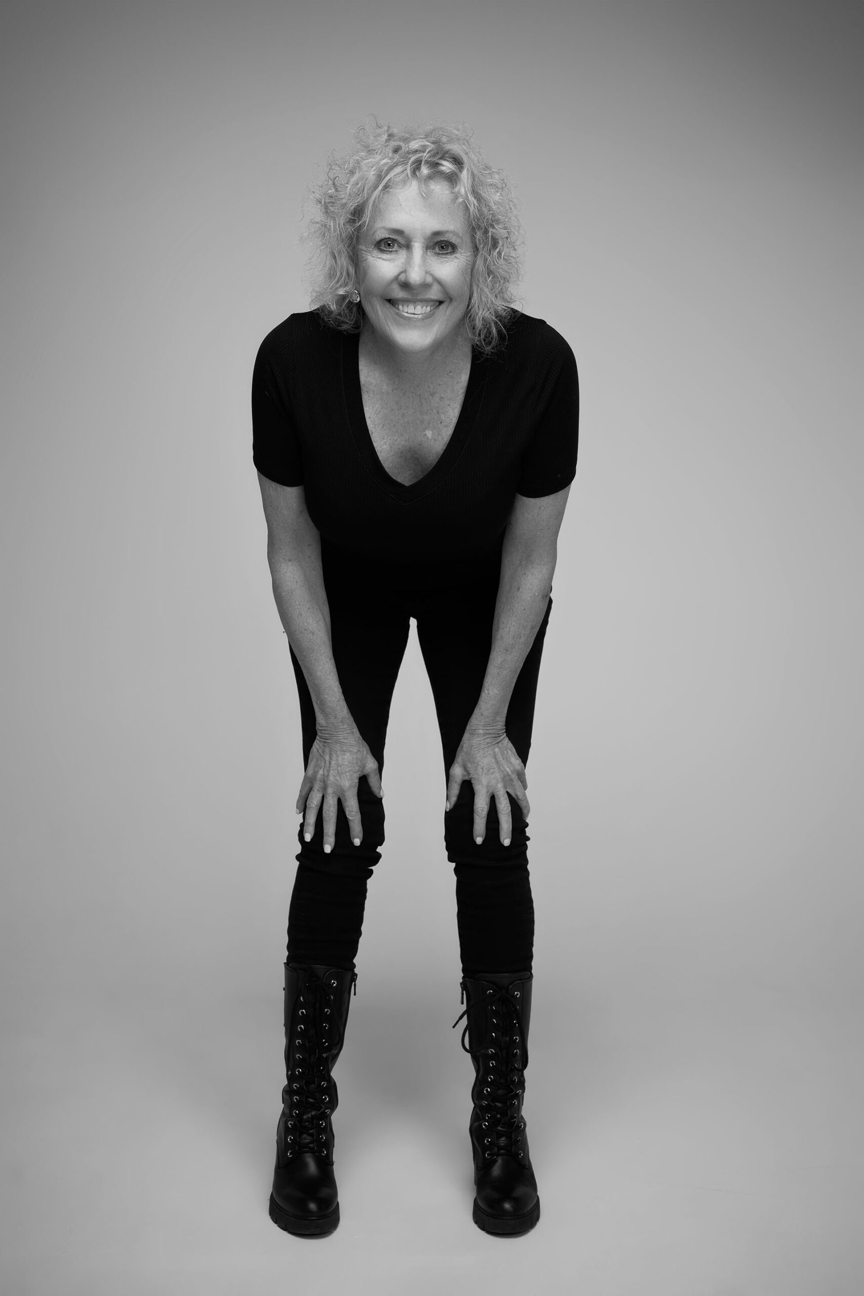 Black-and-white full-body portrait of a woman standing in an all-black outfit