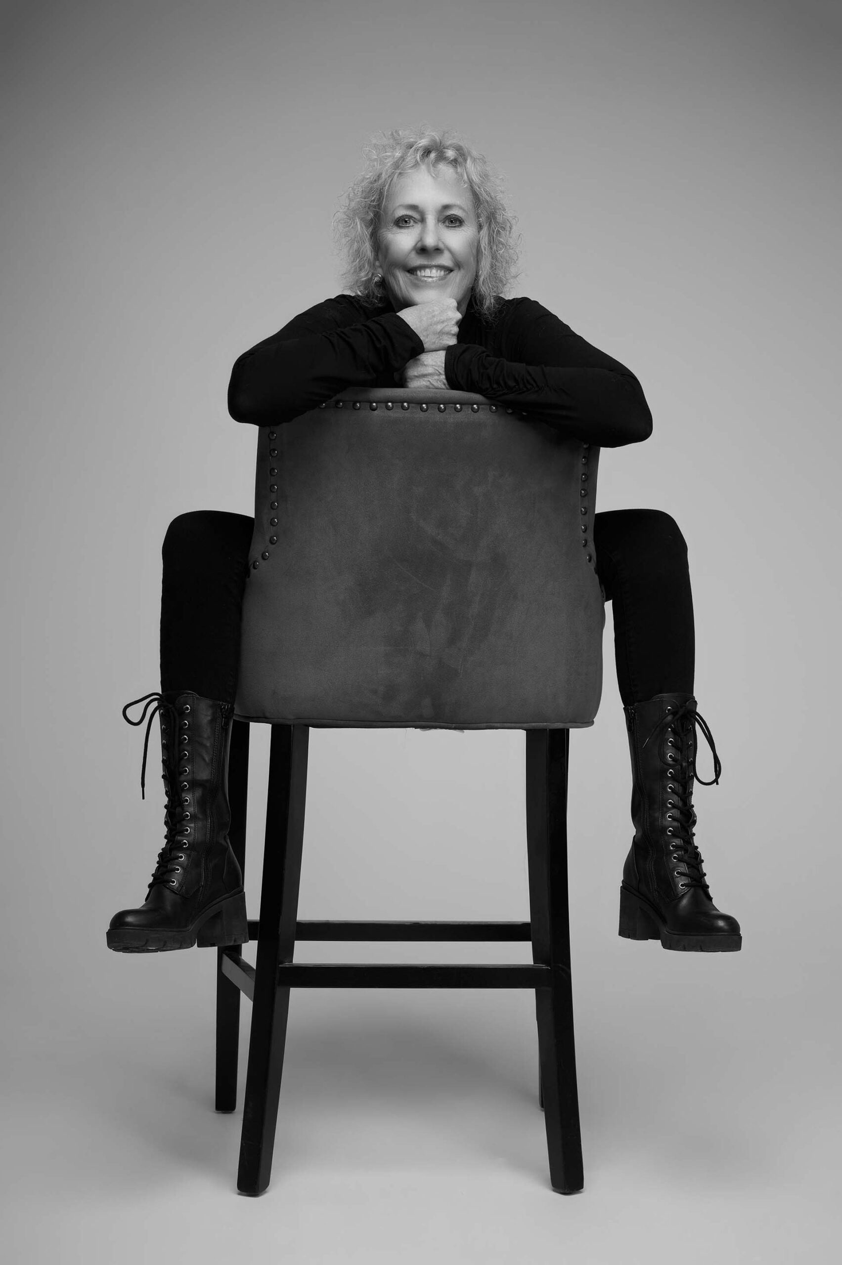Black-and-white portrait of a woman leaning on a chair with arms crossed