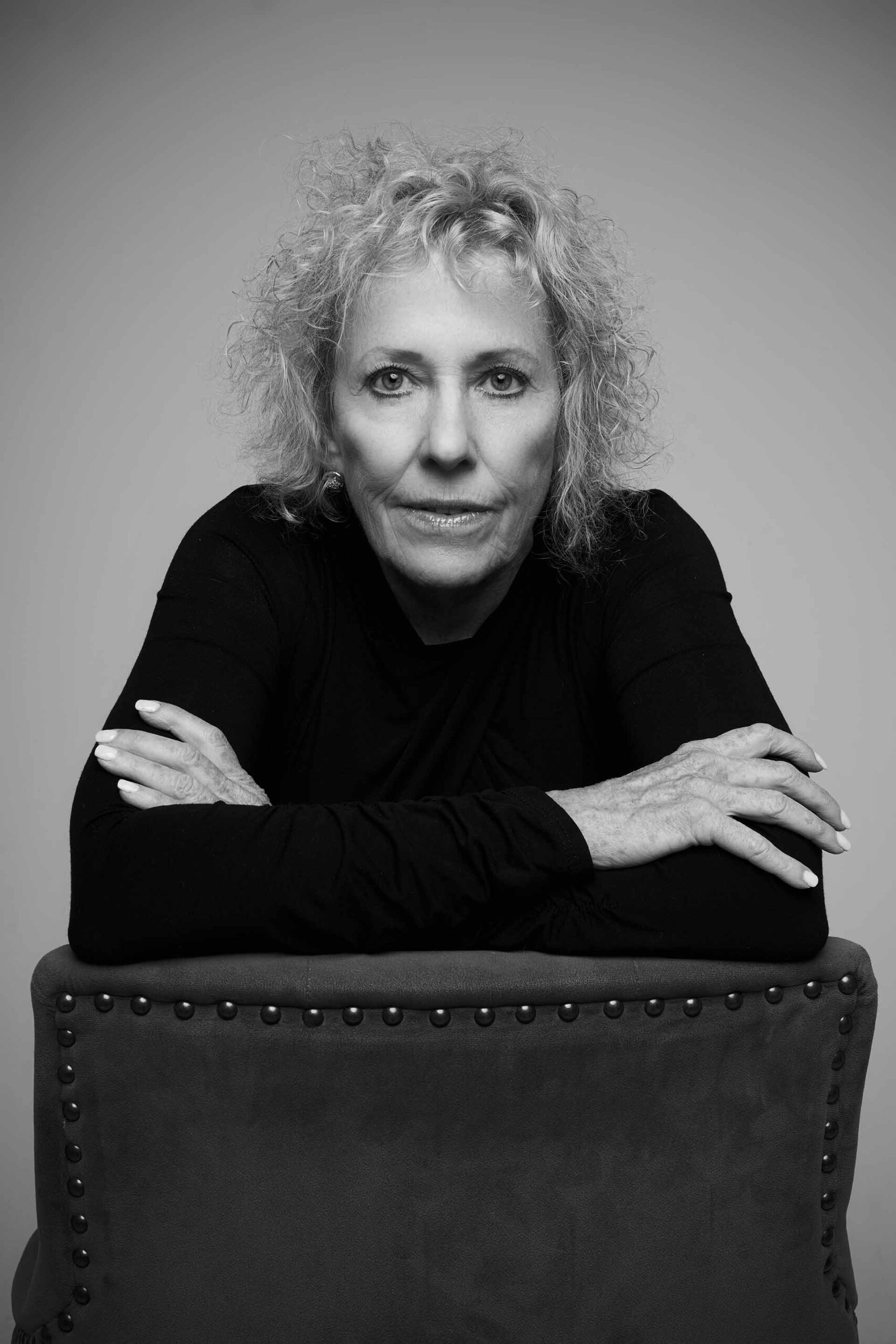 Black-and-white portrait of a woman with hands clasped, statement belt detail