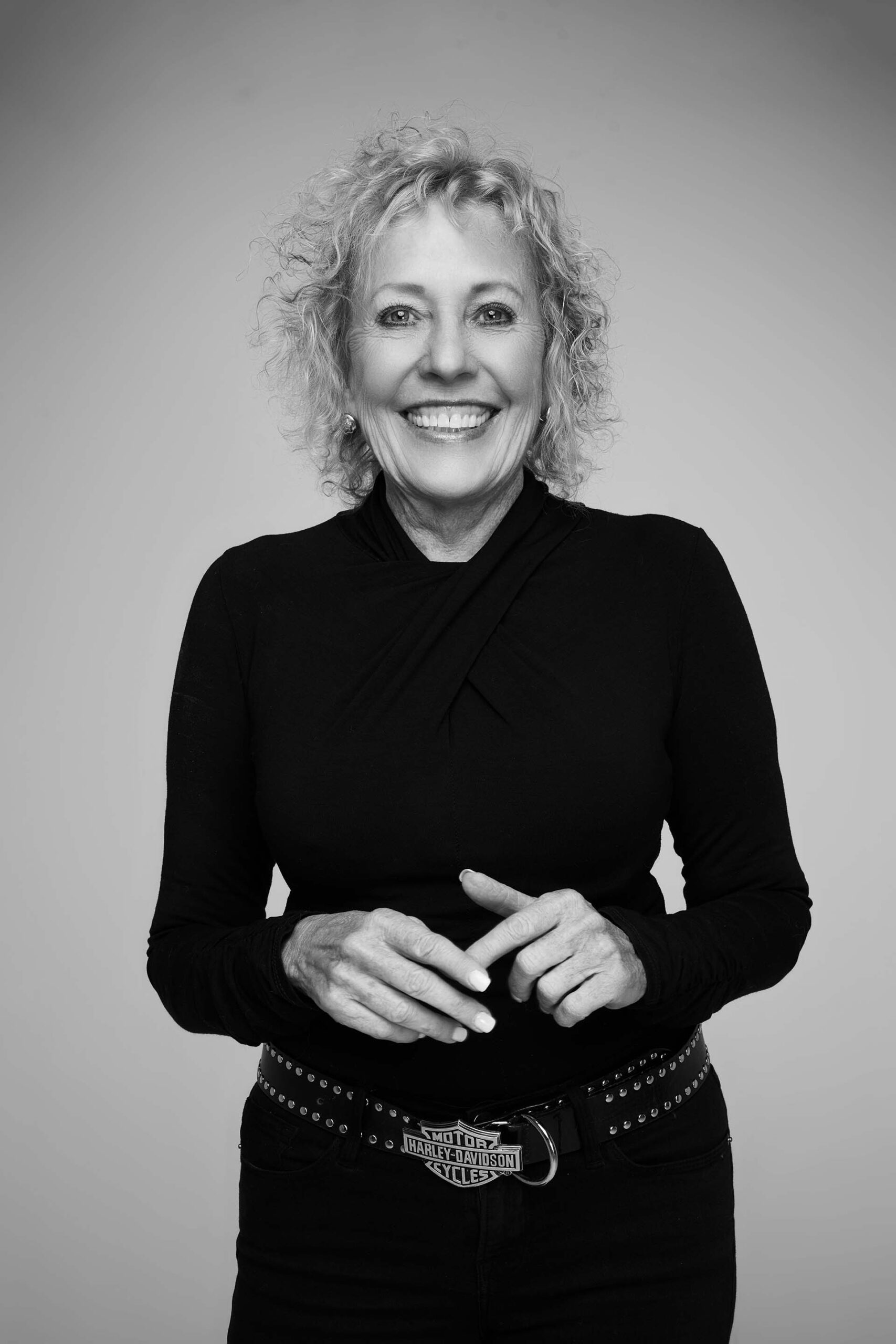 Black-and-white smiling portrait of a woman with fists resting near her waist