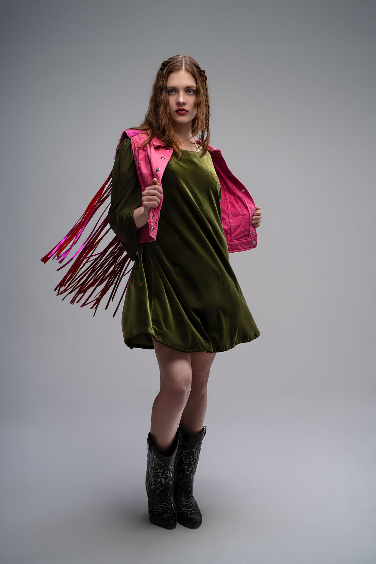 Model in an olive green dress with pink fringe sleeves, studio fashion photography