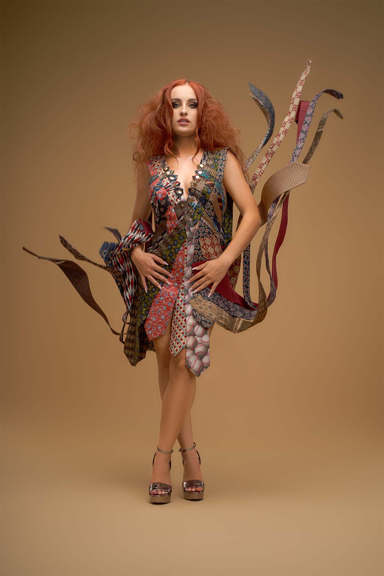 Model in a gown made of ties, beige studio backdrop