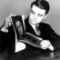 Archival-style black-and-white photo of a man in a suit looking at printed photographs