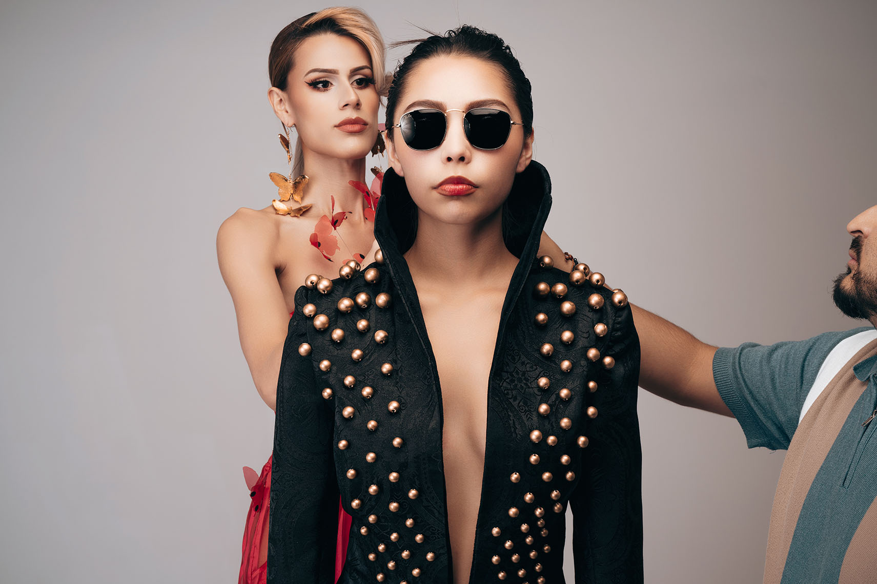 Mauro Look Book Behind-the-Scenes Photography 02 Designer and stylist adjusting a model's studded blazer during a fitting, with a second model in a matching blazer beside her, behind-the-scenes photo