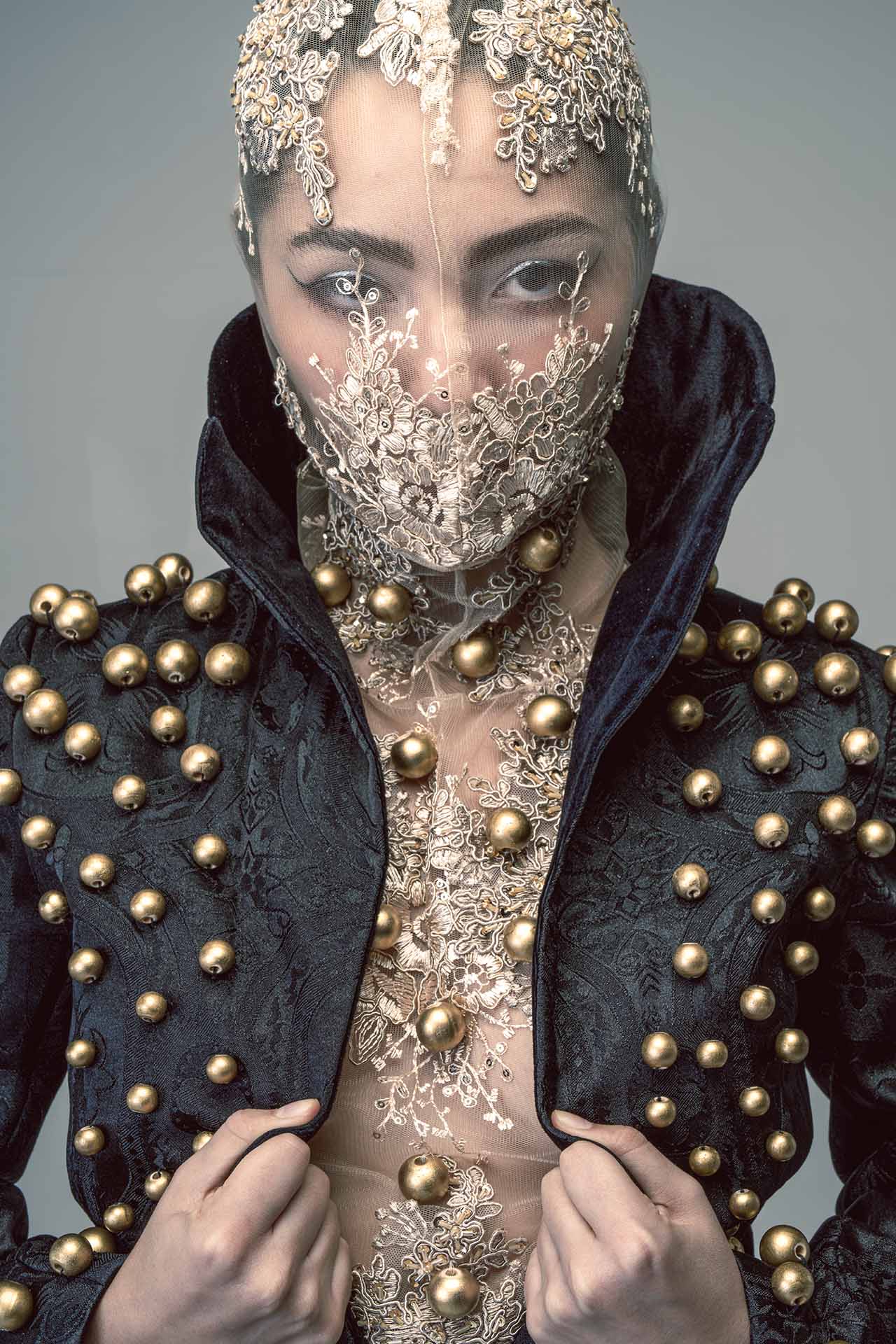 Avant-garde beauty portrait with gold and silver face covering and a studded jacket