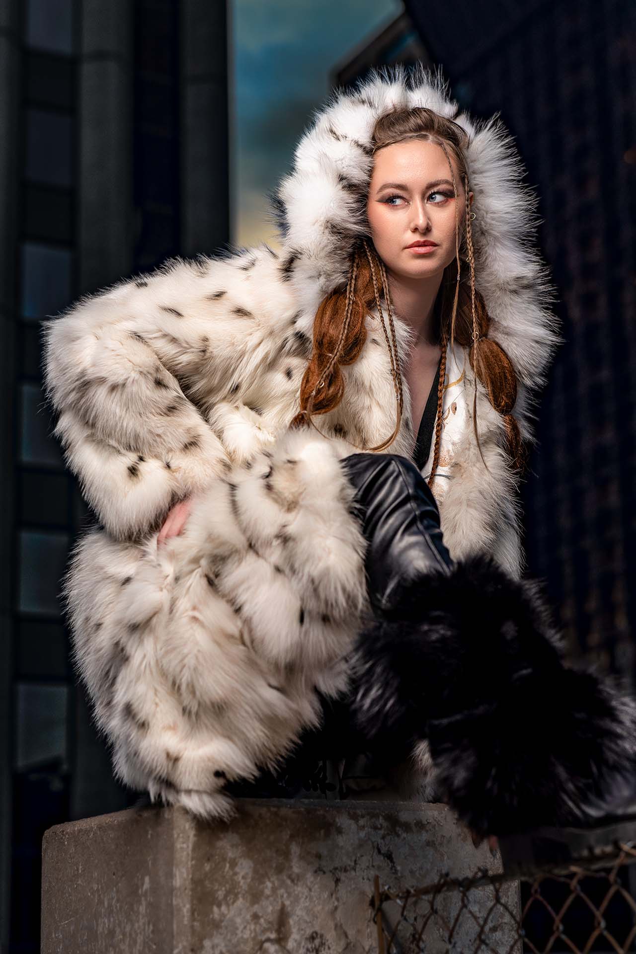 Close portrait of a model in a white fur hood, dramatic urban rooftop editorial photography
