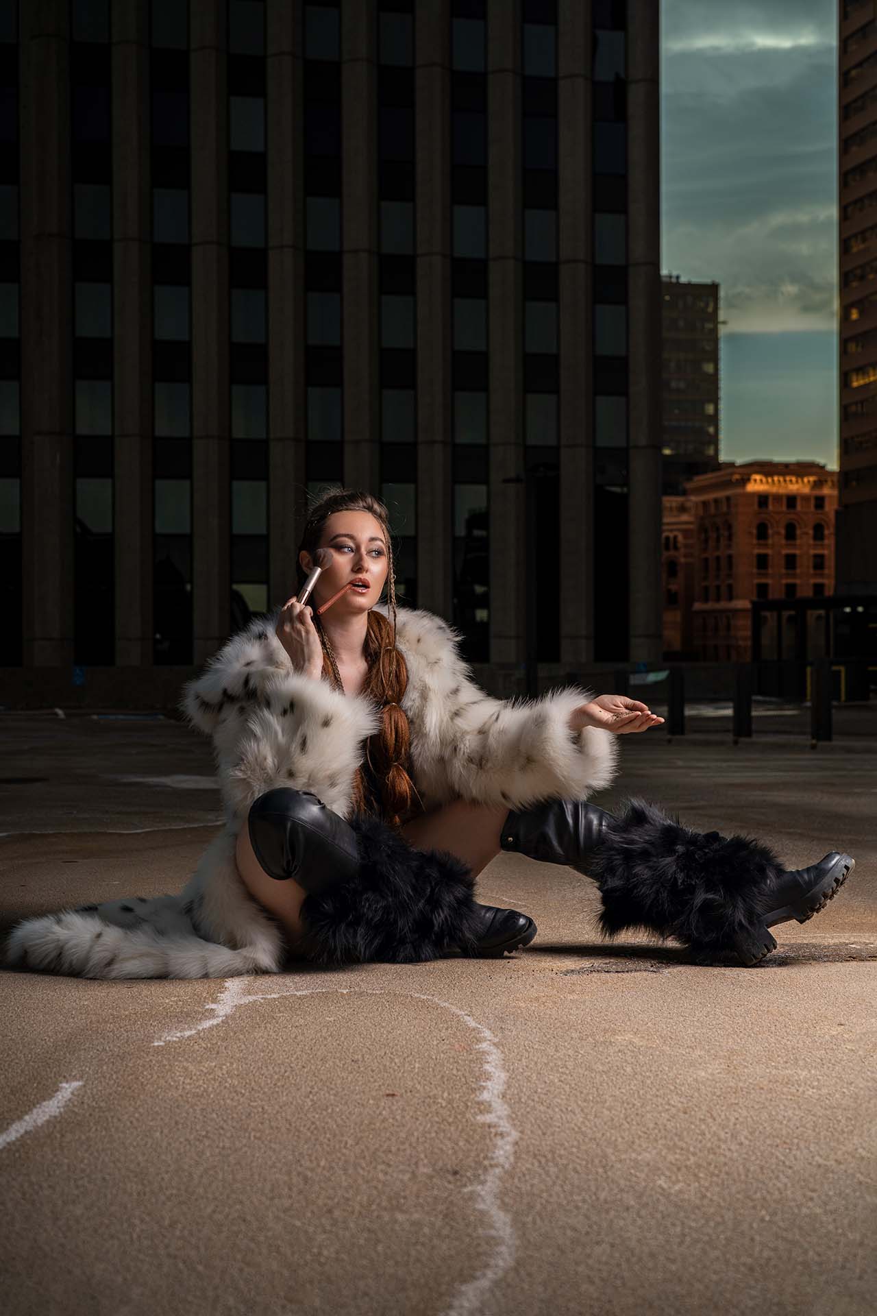 Model seated in a fur coat with an expressive hand gesture, urban rooftop editorial photography