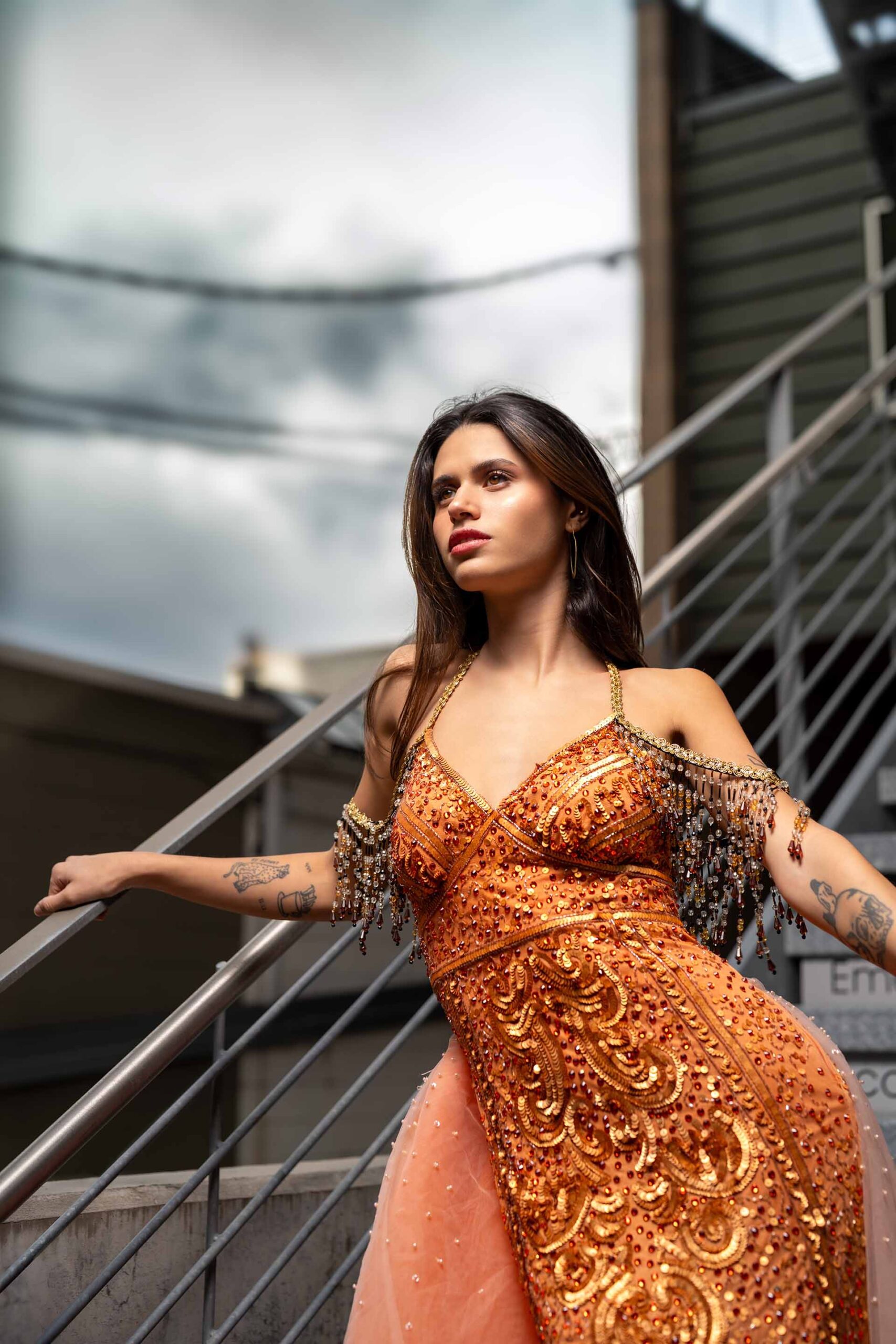 Adi Editorial Fashion Photography 02 Model in an orange and gold sequined gown posing on a metal staircase, editorial fashion photography