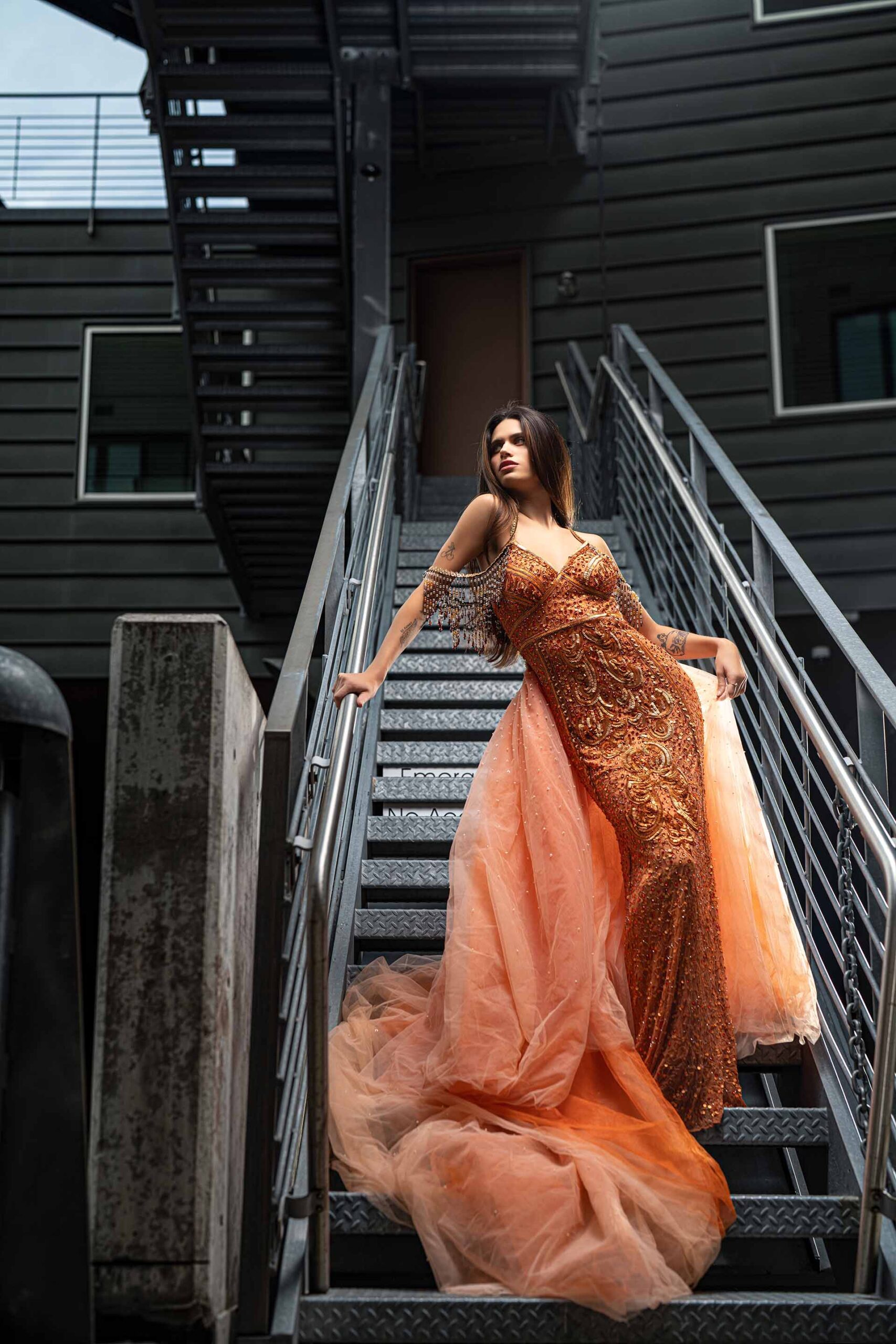 Adi Editorial Fashion Photography 04 Model in a flowing orange gown posing dramatically on an urban metal staircase