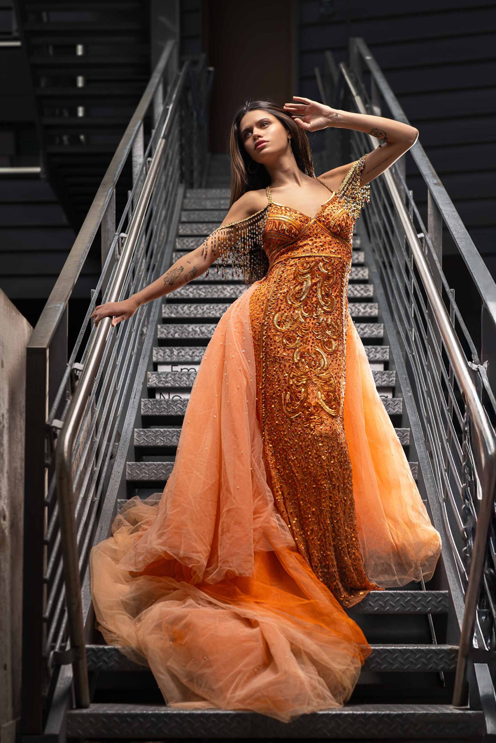 Adi Editorial Fashion Photography 05 Model in a flowing orange gown with arm raised, staircase editorial fashion photography