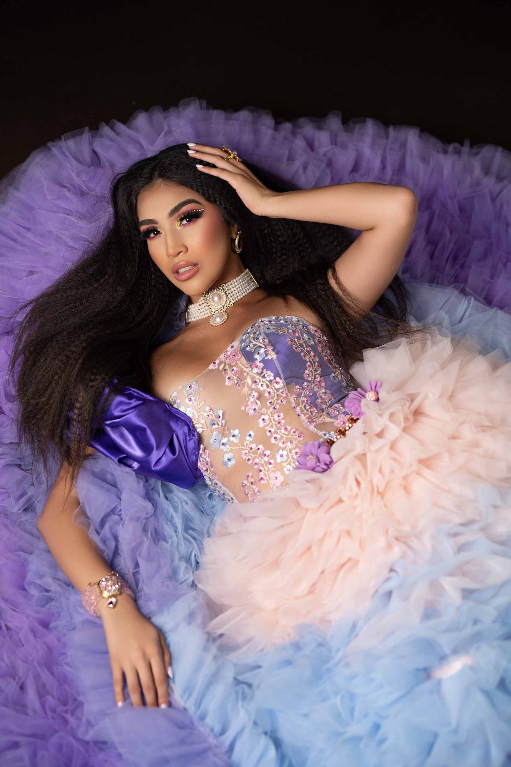 Model lying down in a purple and pink tulle gown with an ornate jeweled bodice at the Cableland venue