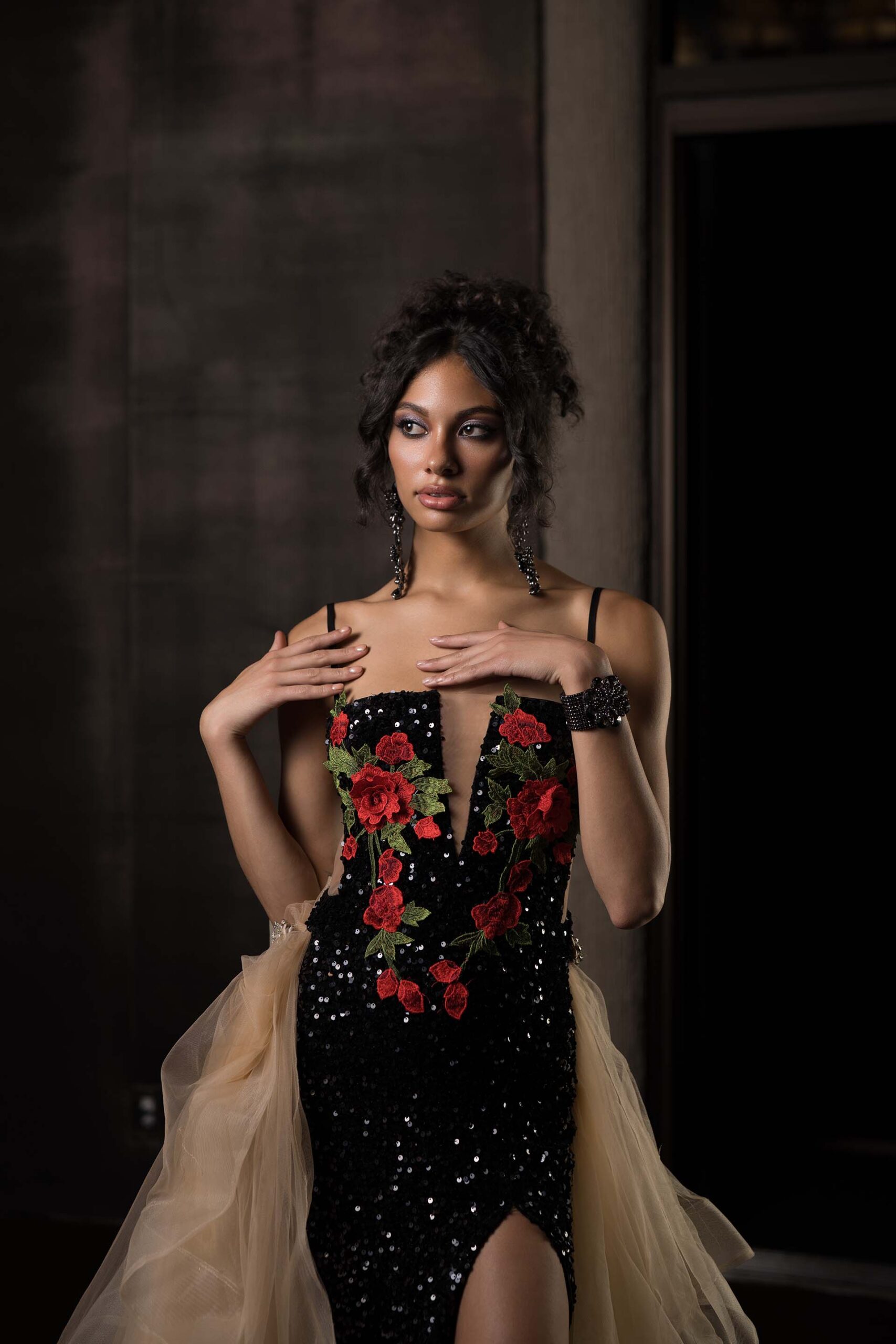 Model in a black floral-embellished gown standing in the Cableland Venue, formal portrait