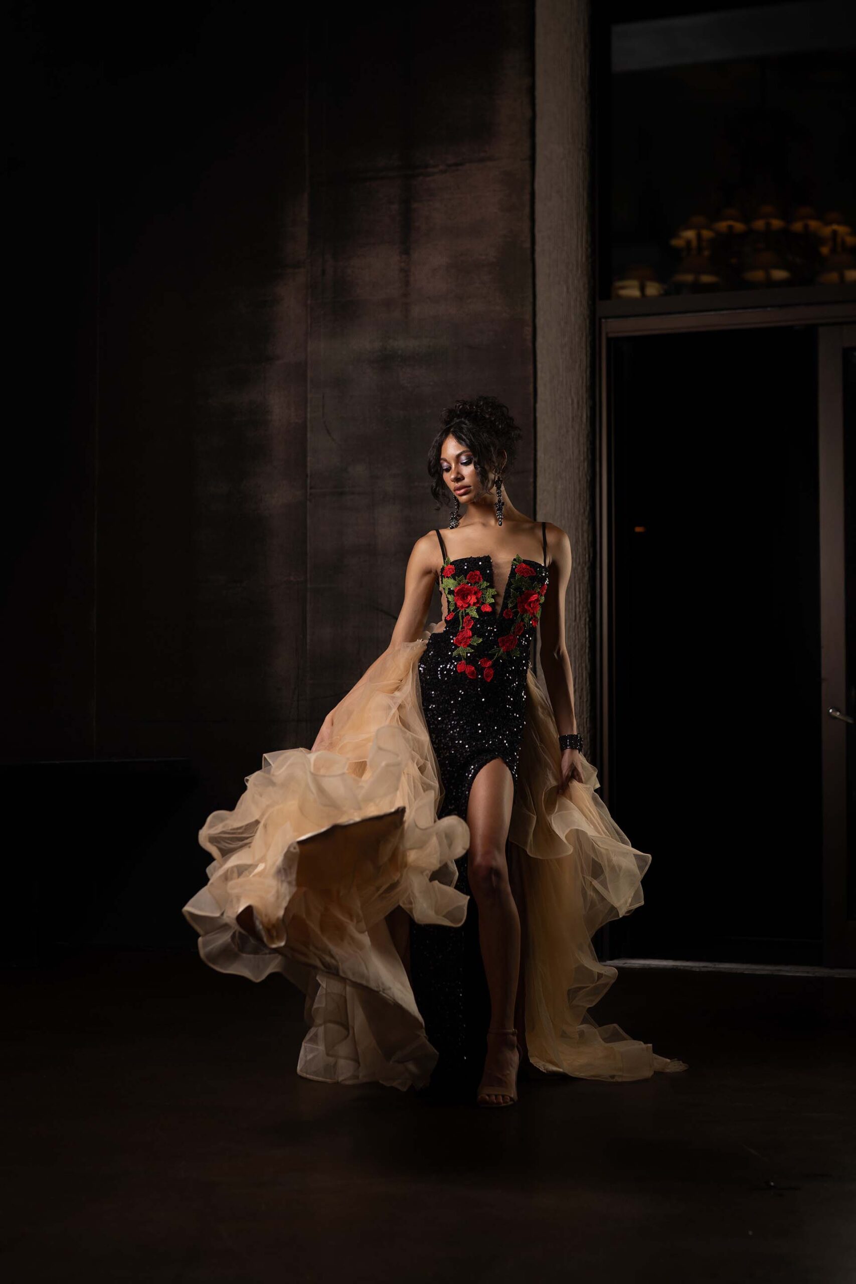 Model in a black gown with a flowing champagne train, alternate pose