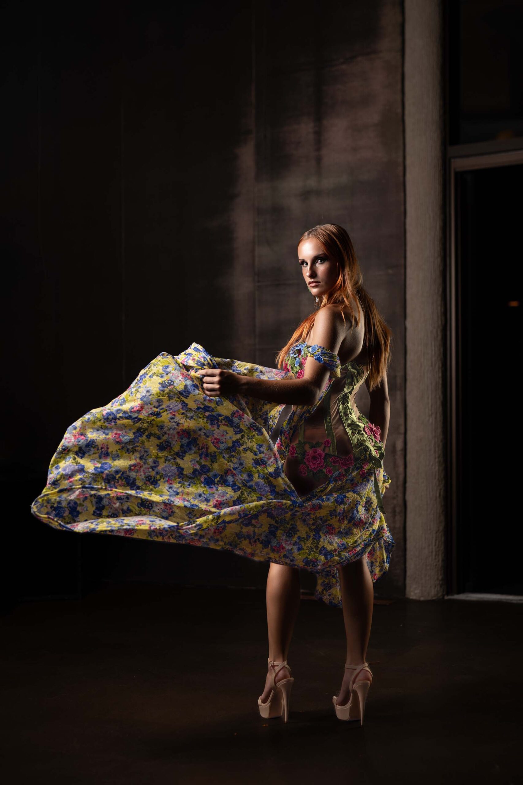Model in a colorful floral-print gown captured mid-twirl, dynamic formal photography