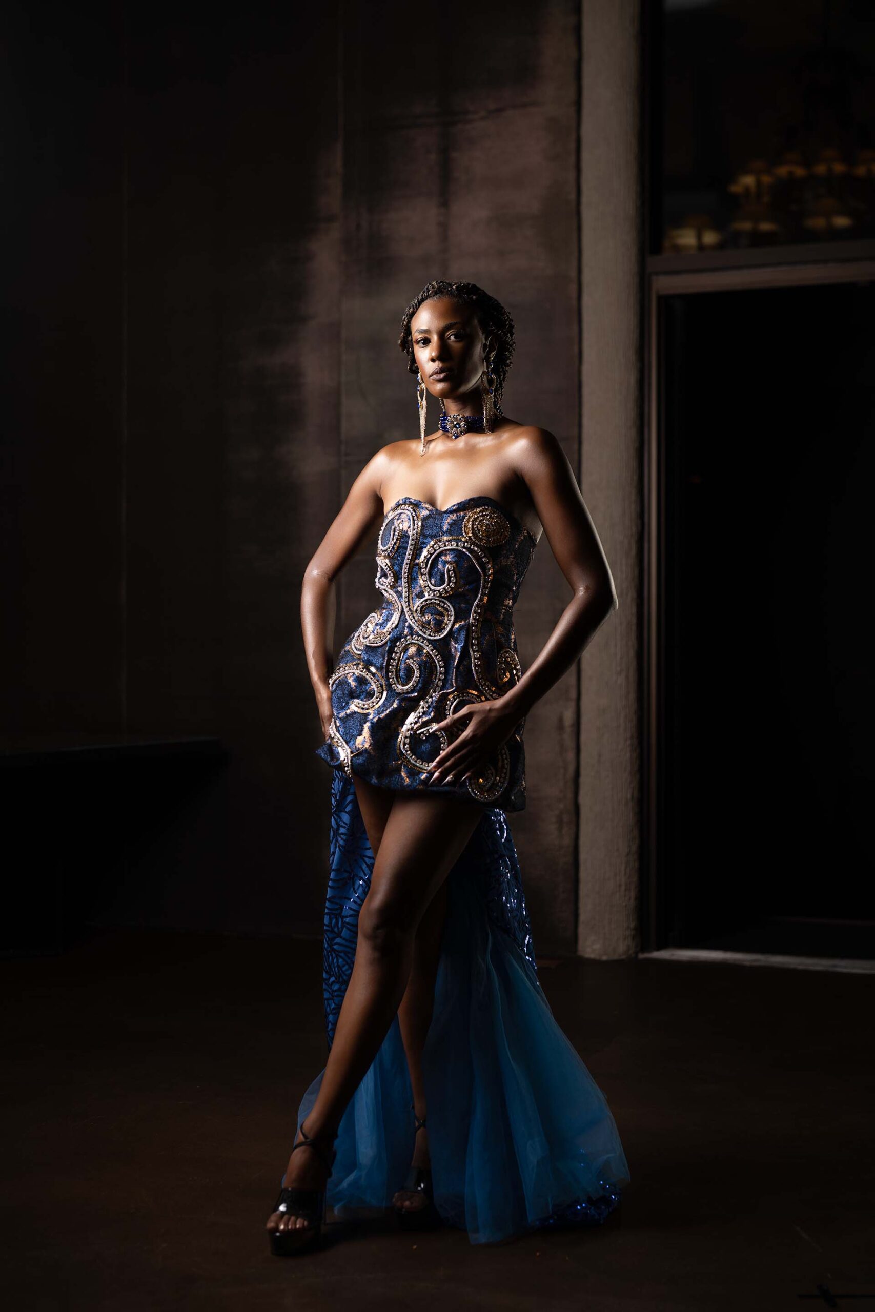 Model in a blue sequined gown with hand on hip, formal studio portrait