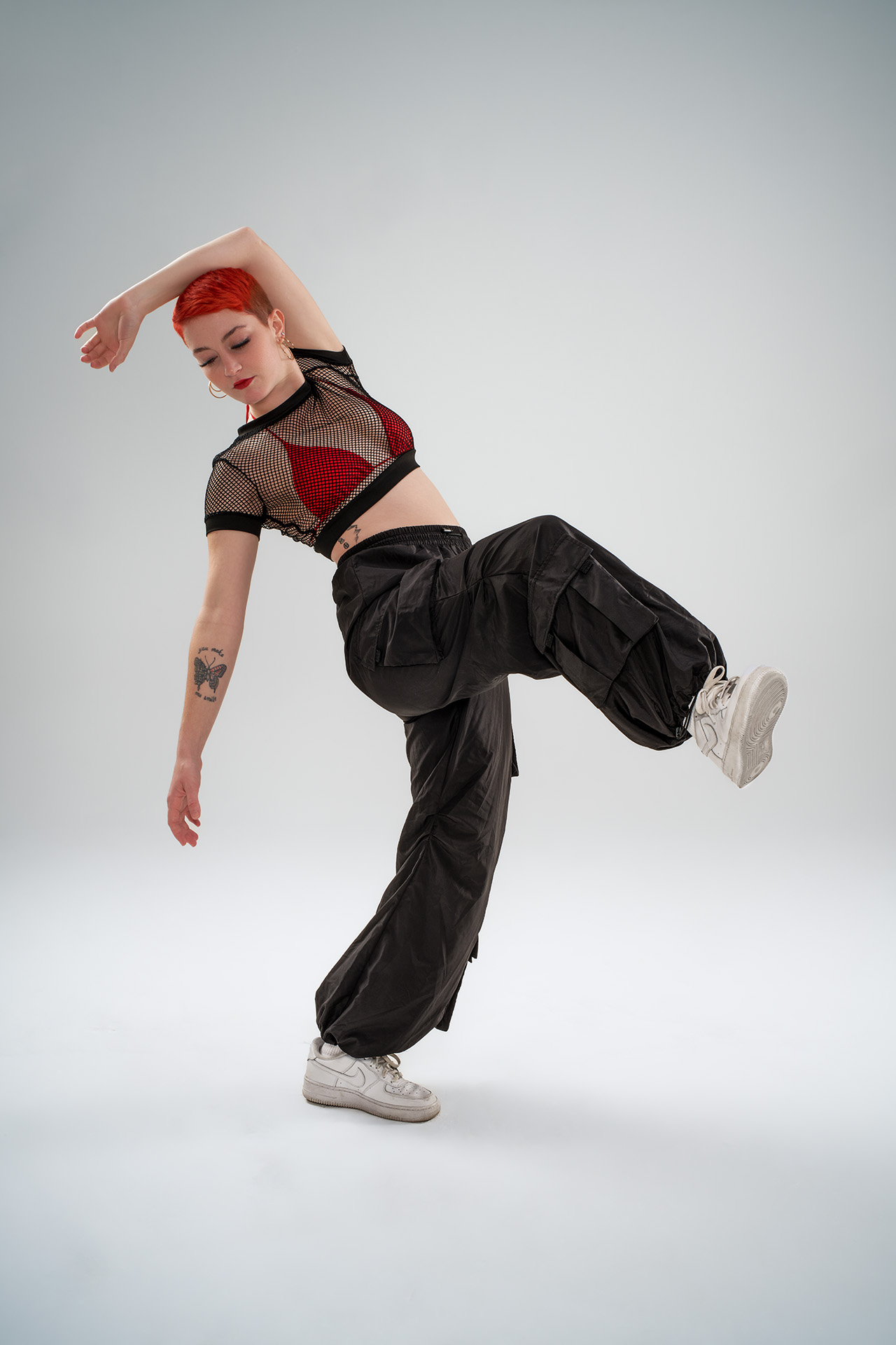 Dancer captured mid-movement in cargo pants and a red bra with black mesh top, dynamic action photography