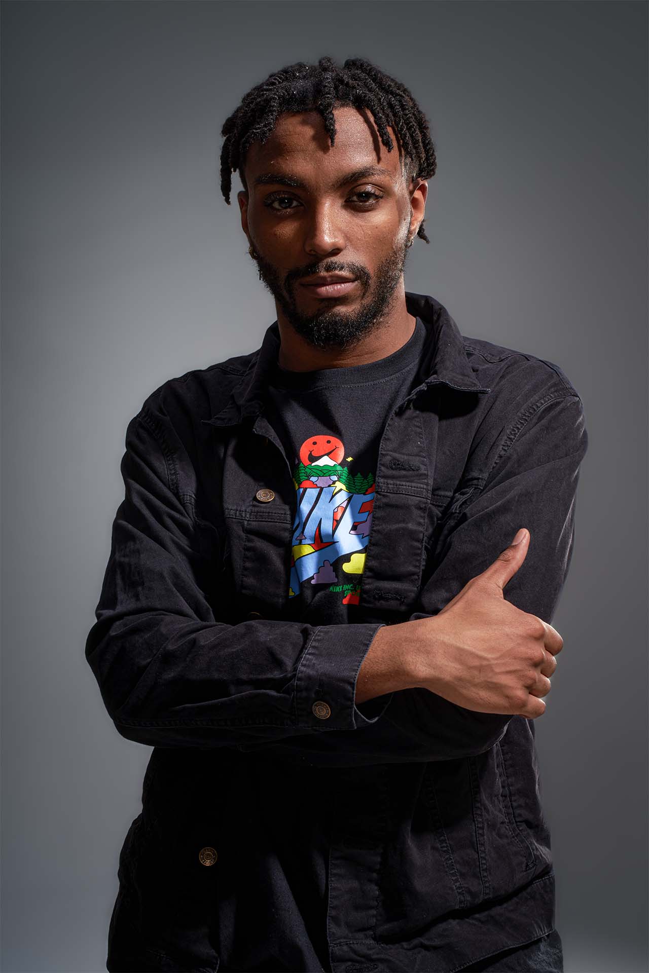 Male dancer in a denim jacket crossed arms, confident studio portrait