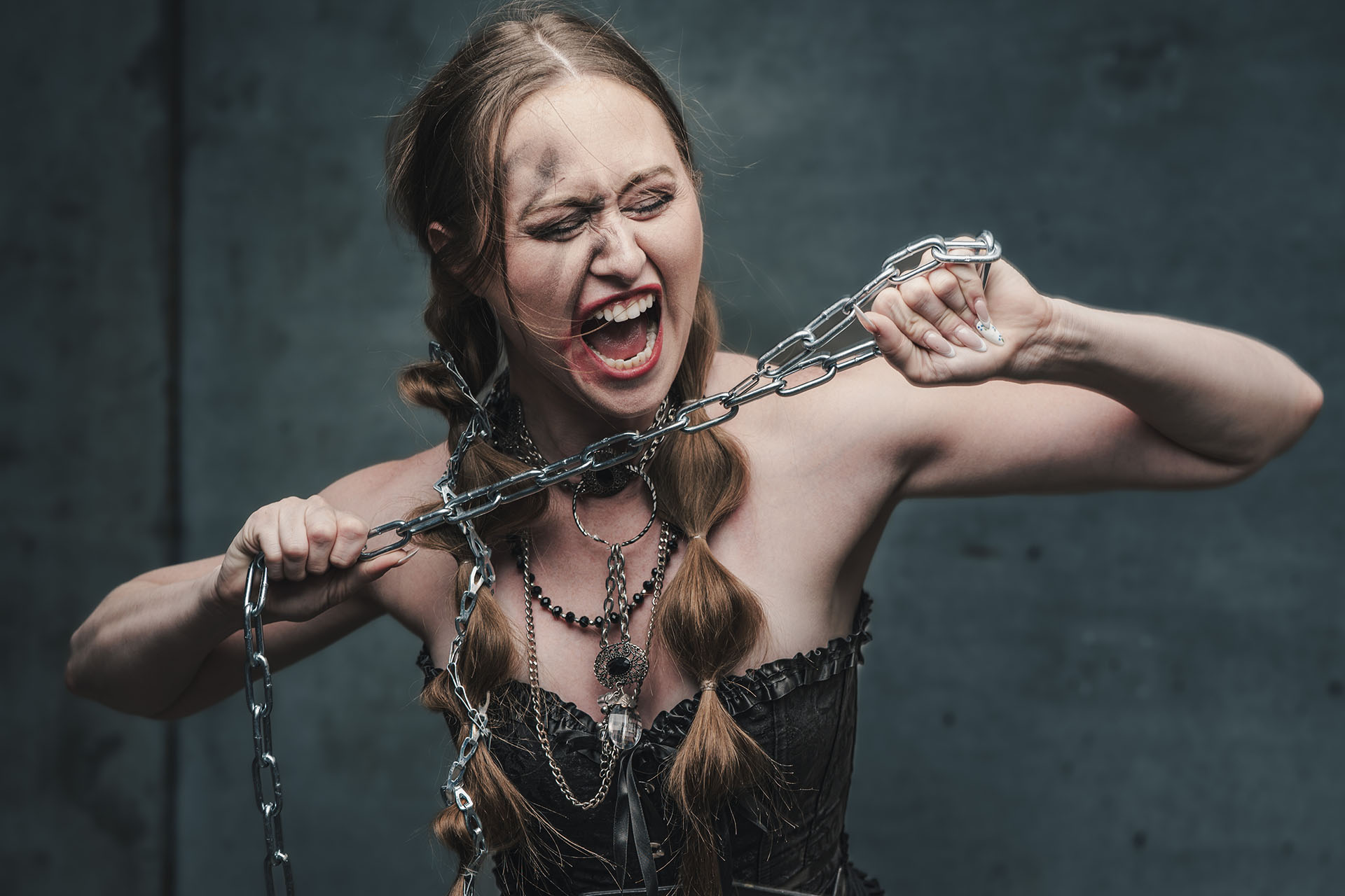 Dramatic editorial portrait of a woman with chains wrapped around her wrists, intense expression