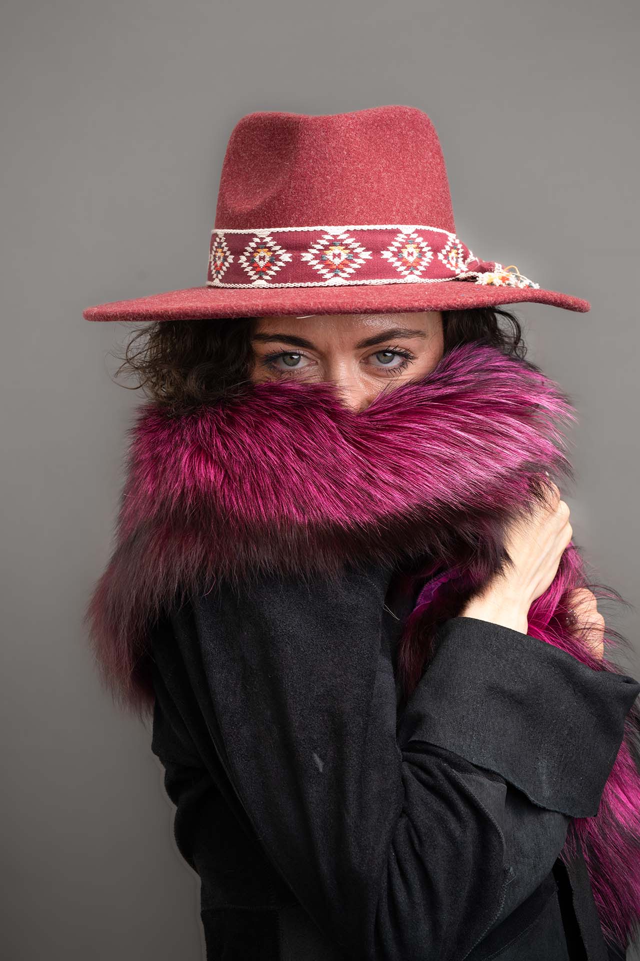 Model in a pink fedora hat and fuchsia fur coat, playful editorial portrait
