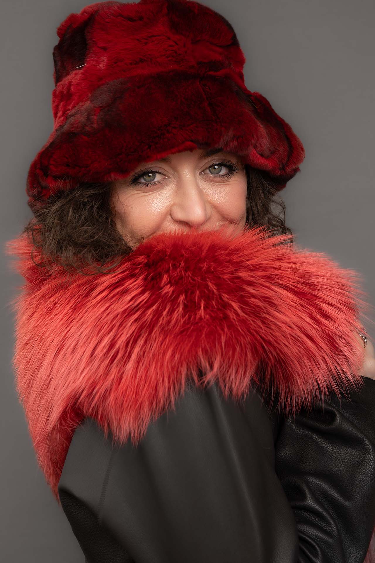 Model in a red fur hat and matching fur coat, close studio portrait