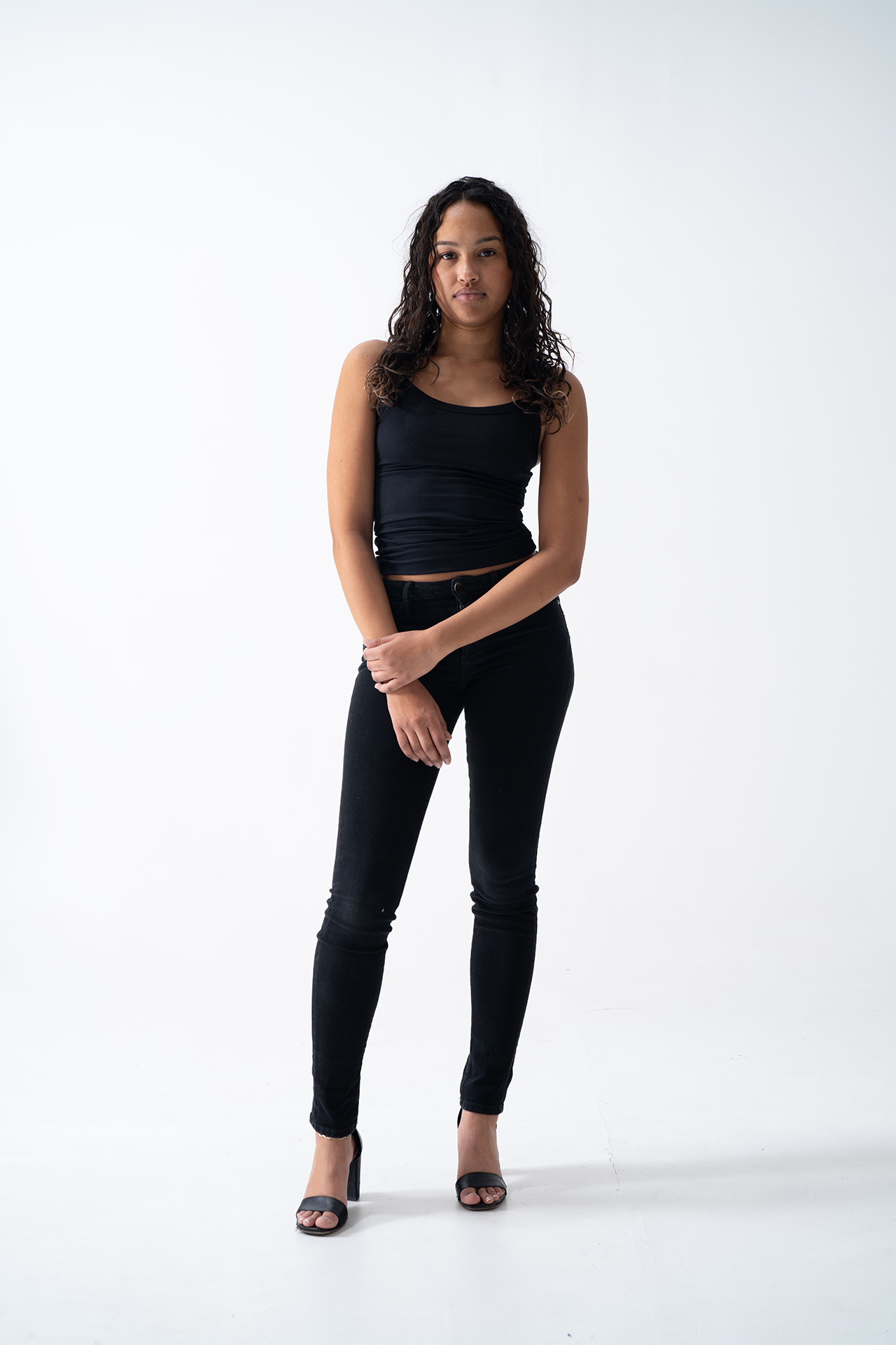 Full-body model portfolio digital in a black outfit, front-facing, hands clasped