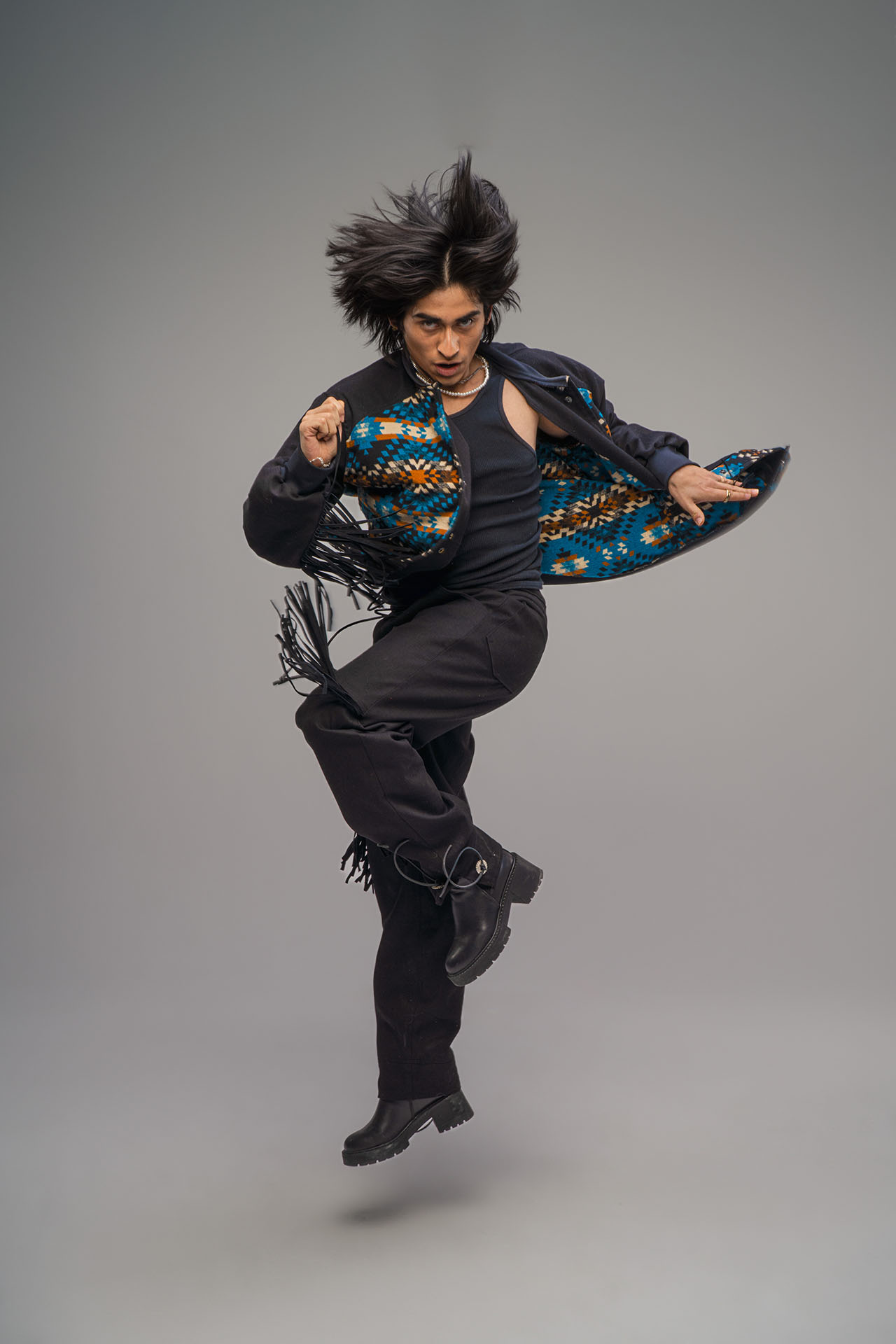 Model captured mid-jump wearing a fringe jacket, dynamic dance-inspired editorial photography