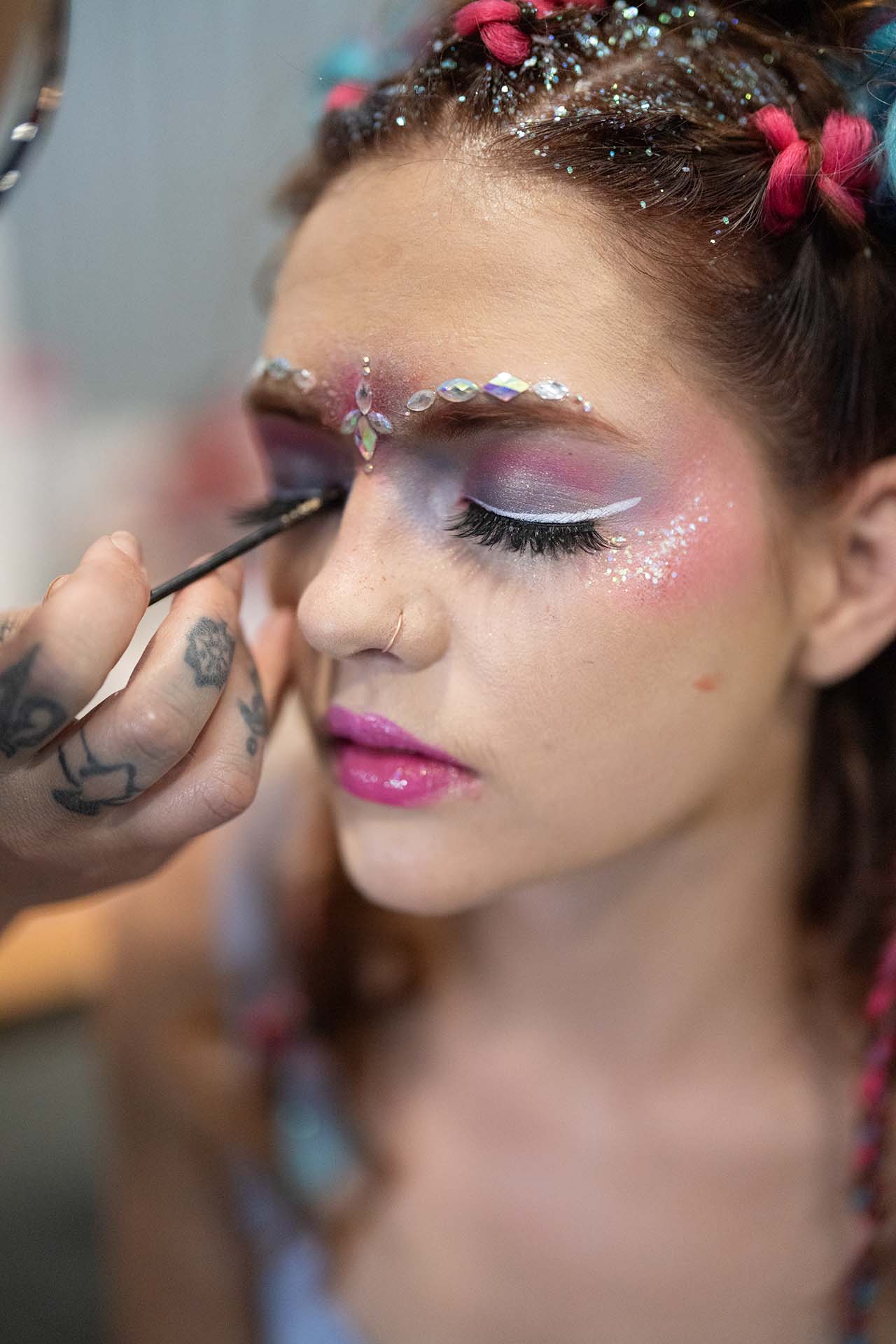Close-up backstage photo of a model with glitter and rhinestone eye makeup at Denver Fashion Week
