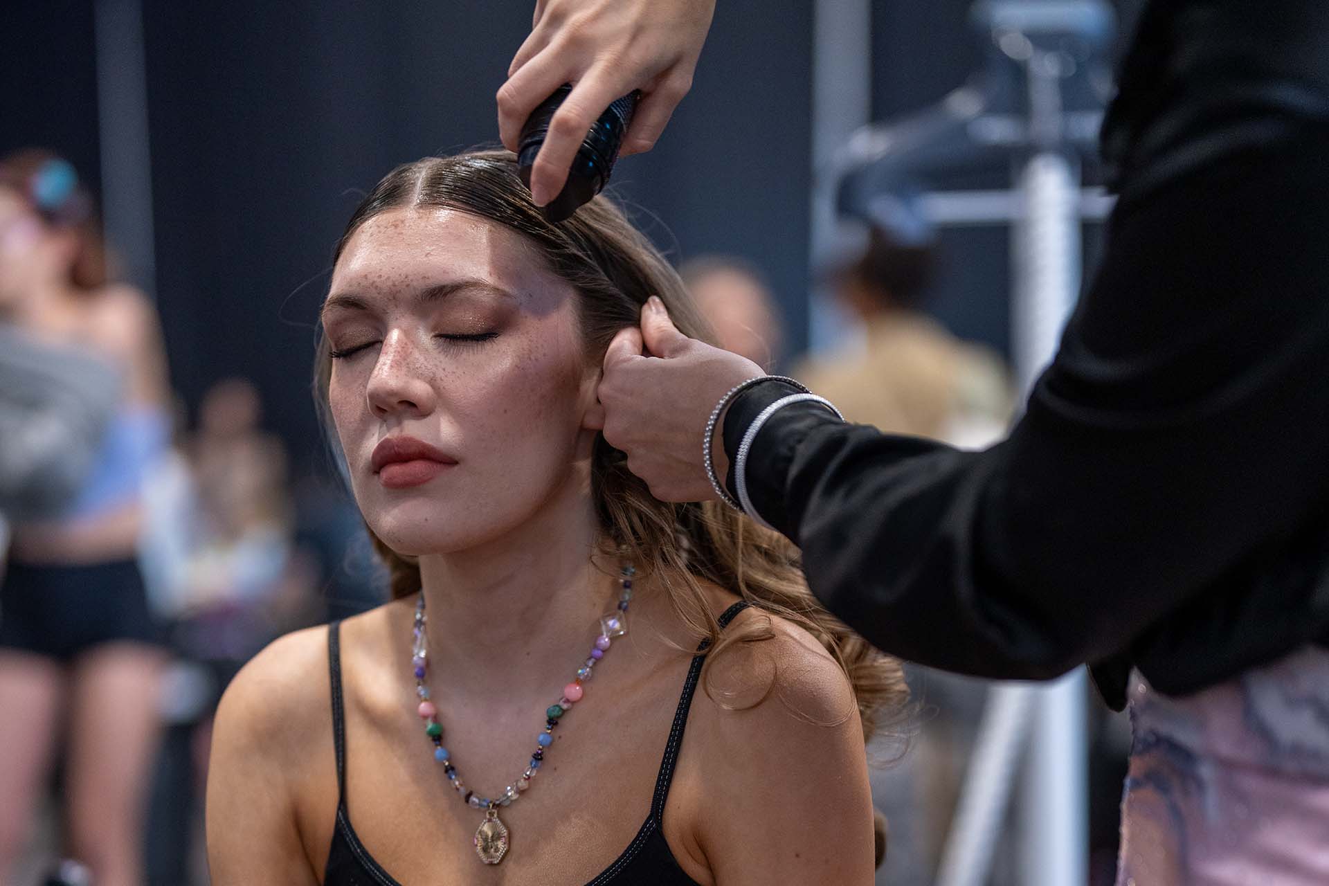 Backstage photo of a stylist working on a model's hair, second look, Denver Fashion Week