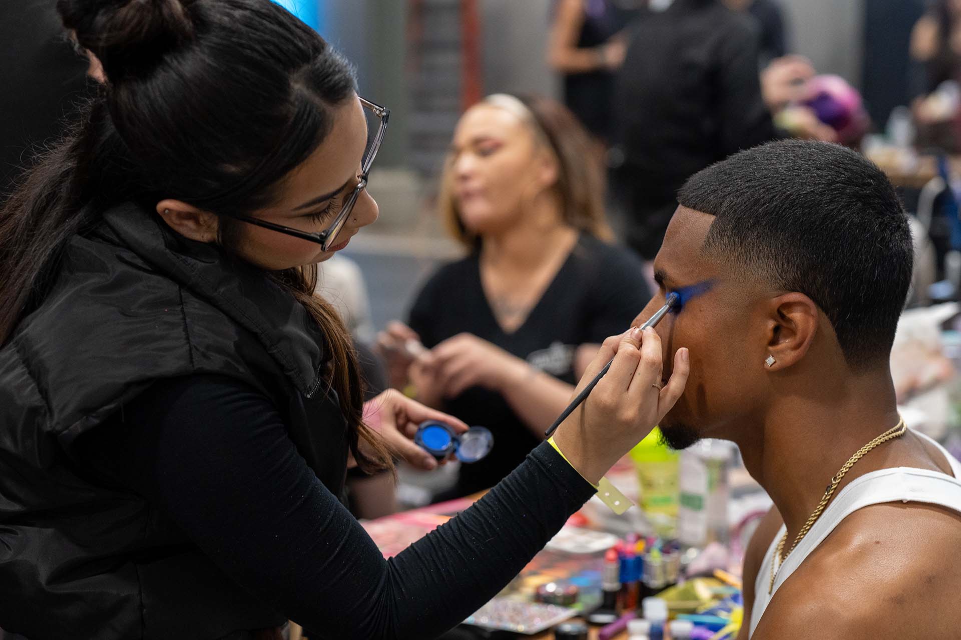 Backstage photo of a makeup artist applying makeup to a model at Denver Fashion Week