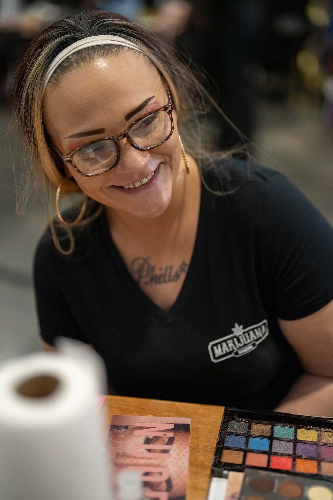 Smiling makeup artist in glasses and her makeup palette backstage at Denver Fashion Week