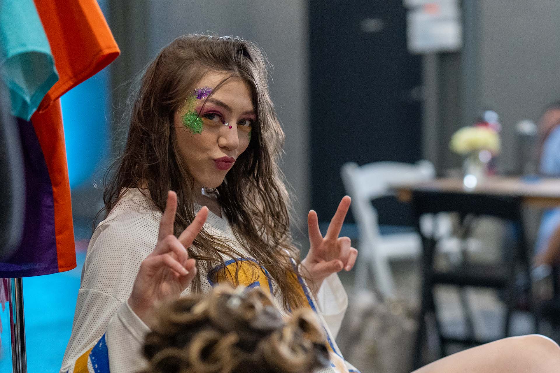 Candid backstage photo of a model making a peace sign in a colorful outfit