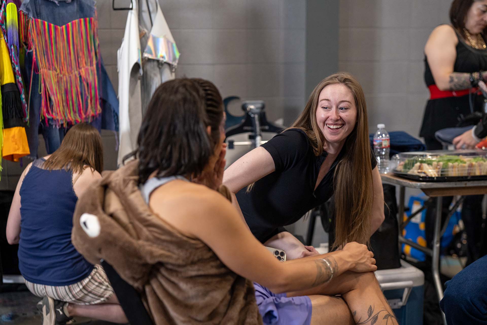 Candid backstage photo of two models sharing a playful moment at Denver Fashion Week