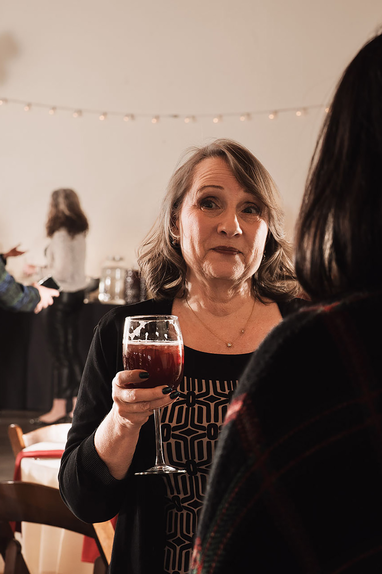 Candid event photo of a woman holding a glass of wine at a gala reception