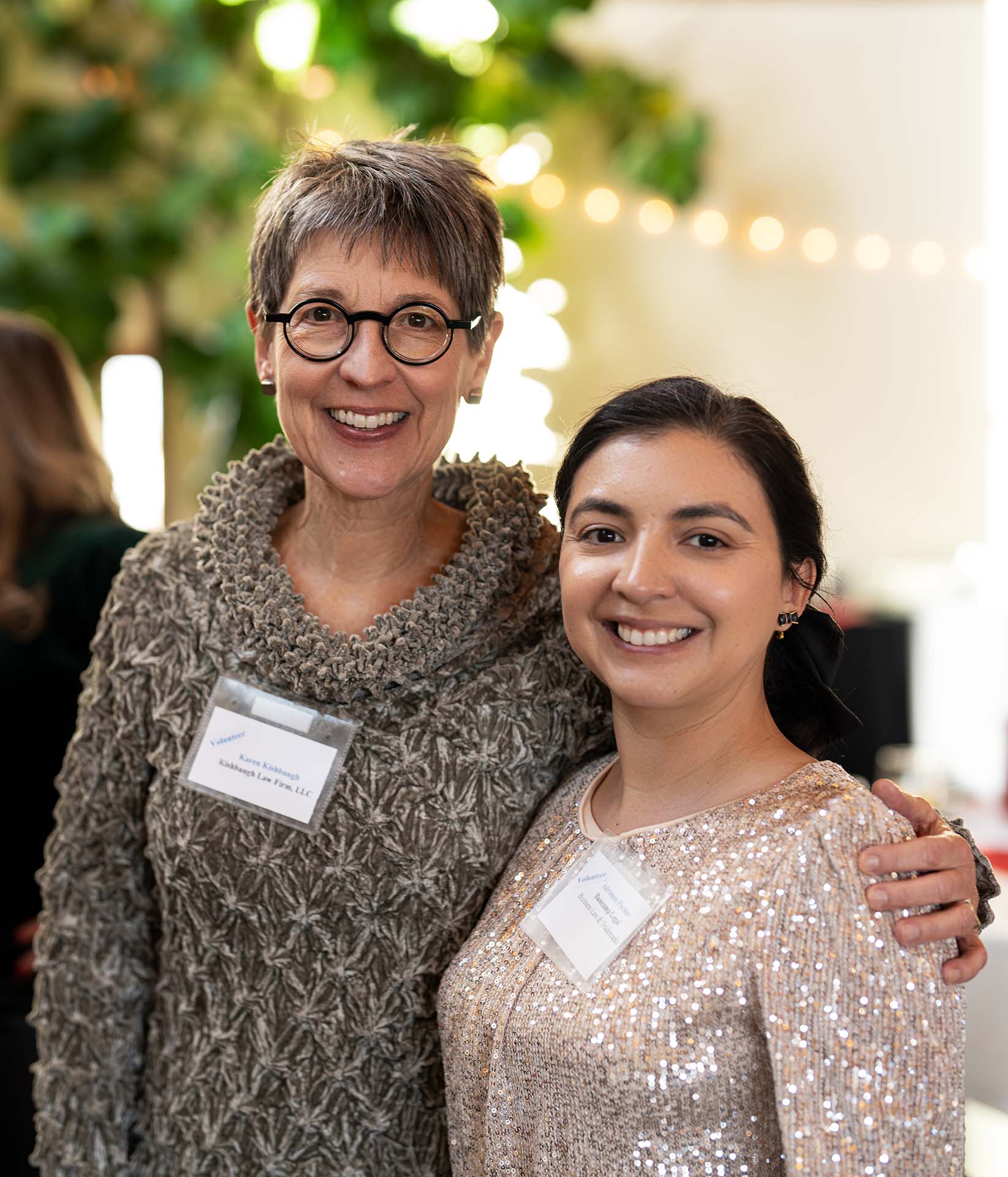 Two women posing together and smiling at an event, wearing name tags