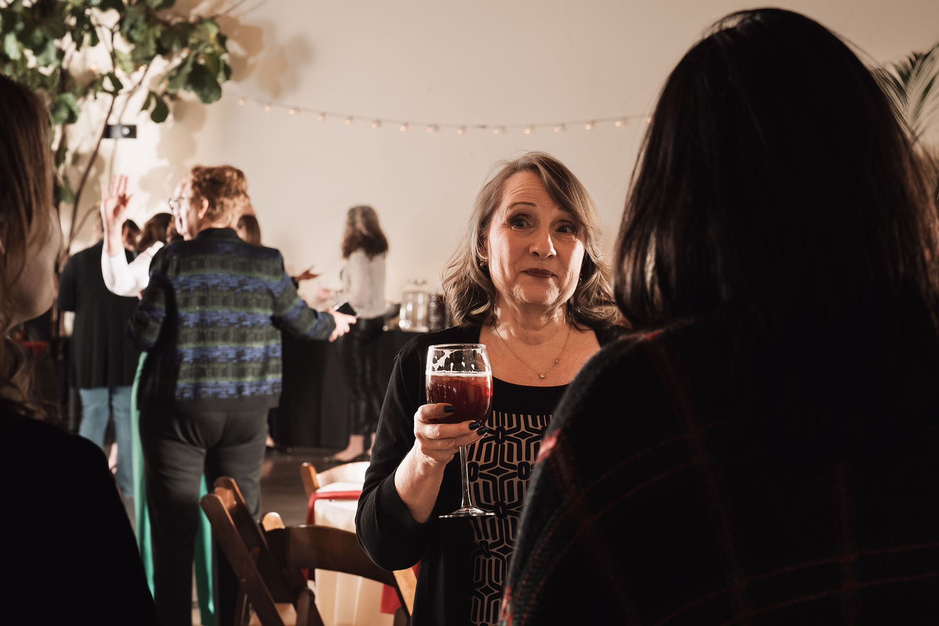 Candid photo of a woman holding a drink while mingling at an event