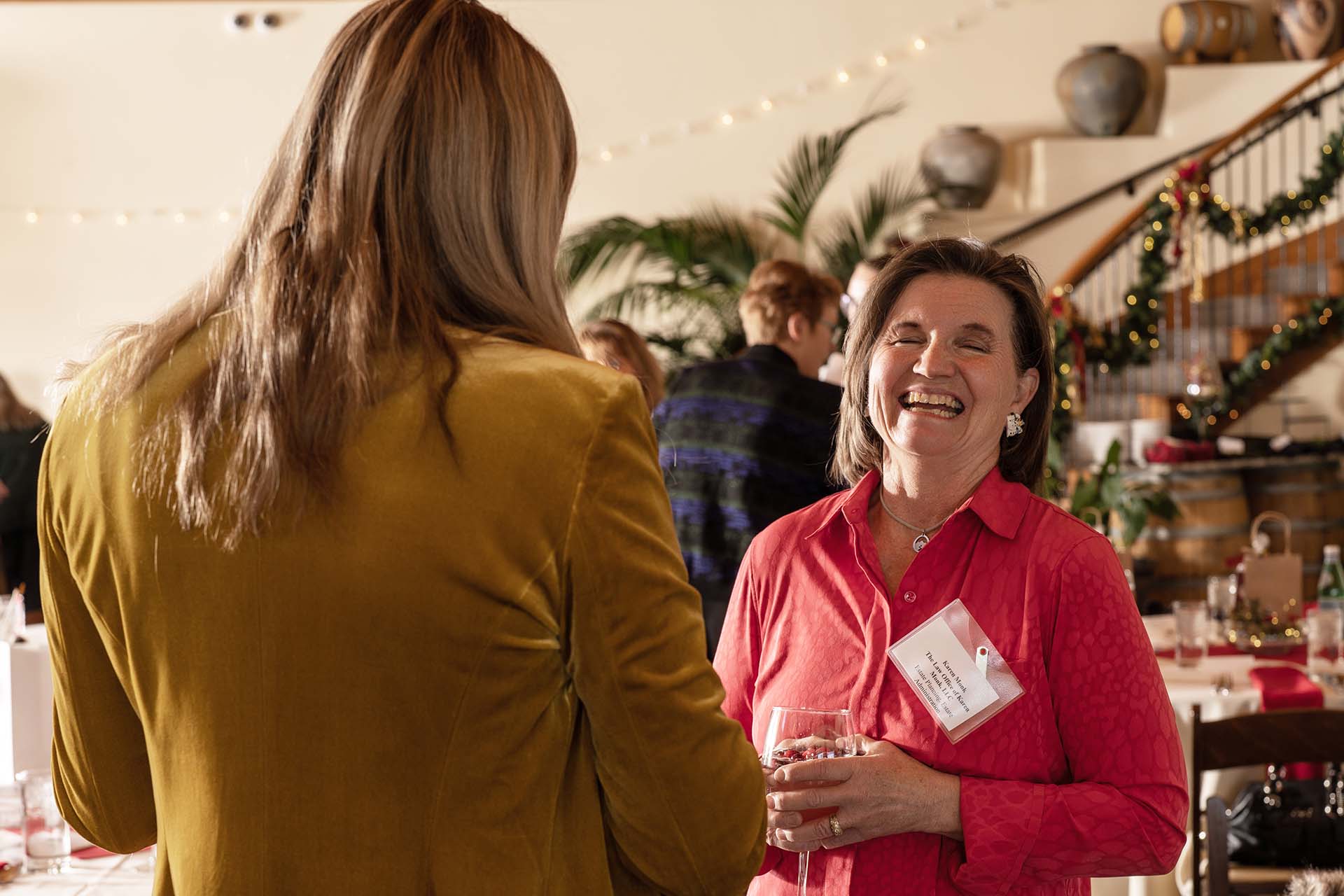 Candid photo of two guests talking at an event, one in a mustard blazer