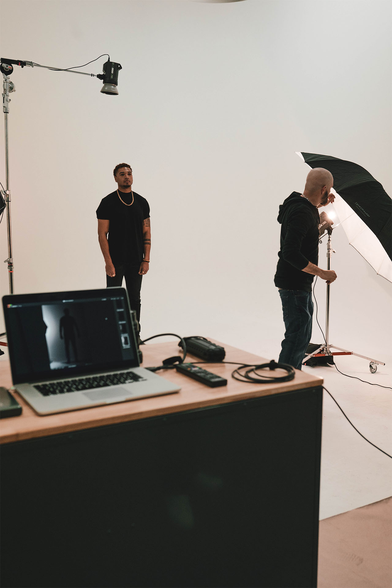 Behind-the-scenes studio photo of photographer working with a tethered laptop setup