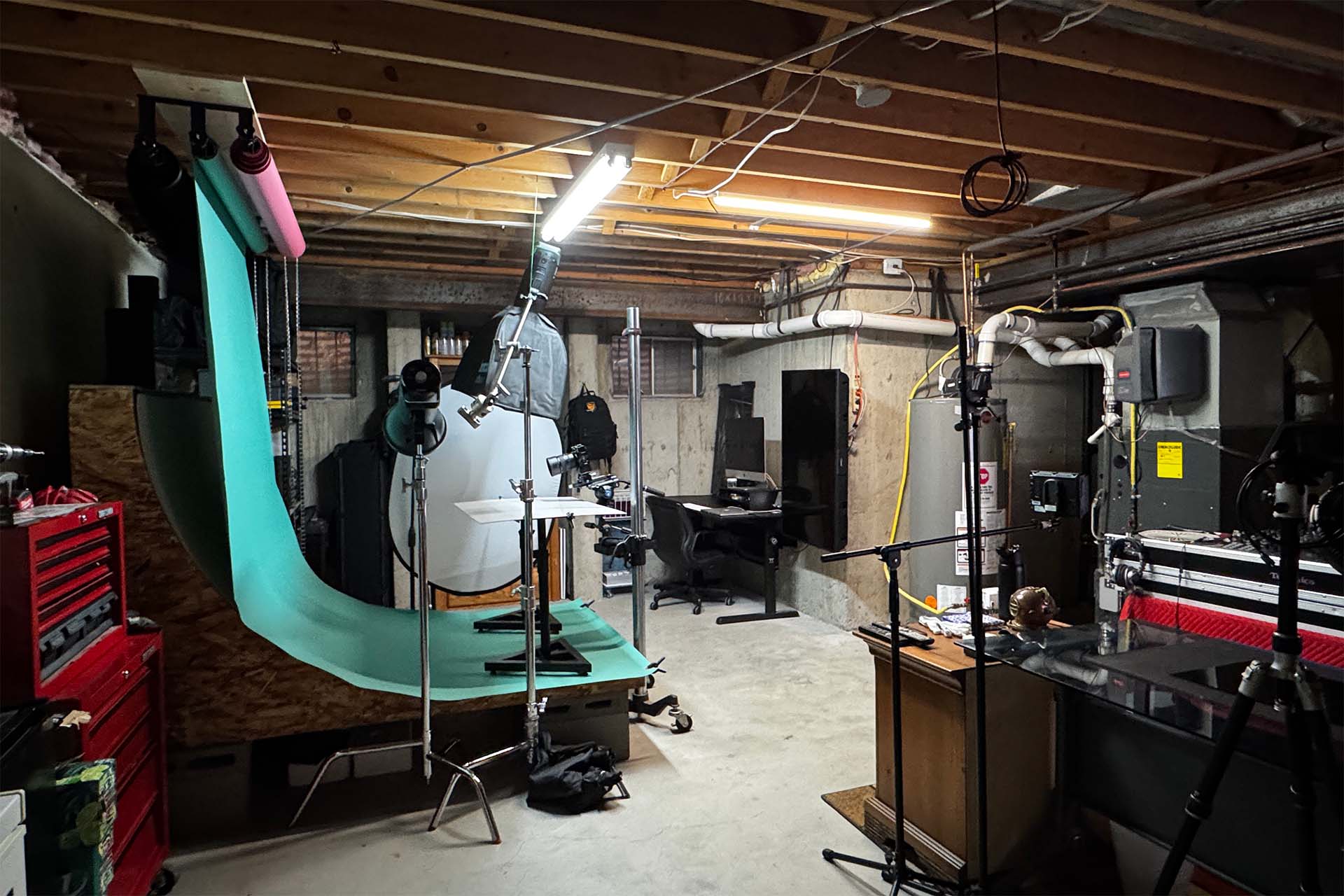 Behind-the-scenes photo of a studio basement set with a teal fabric backdrop and camera equipment