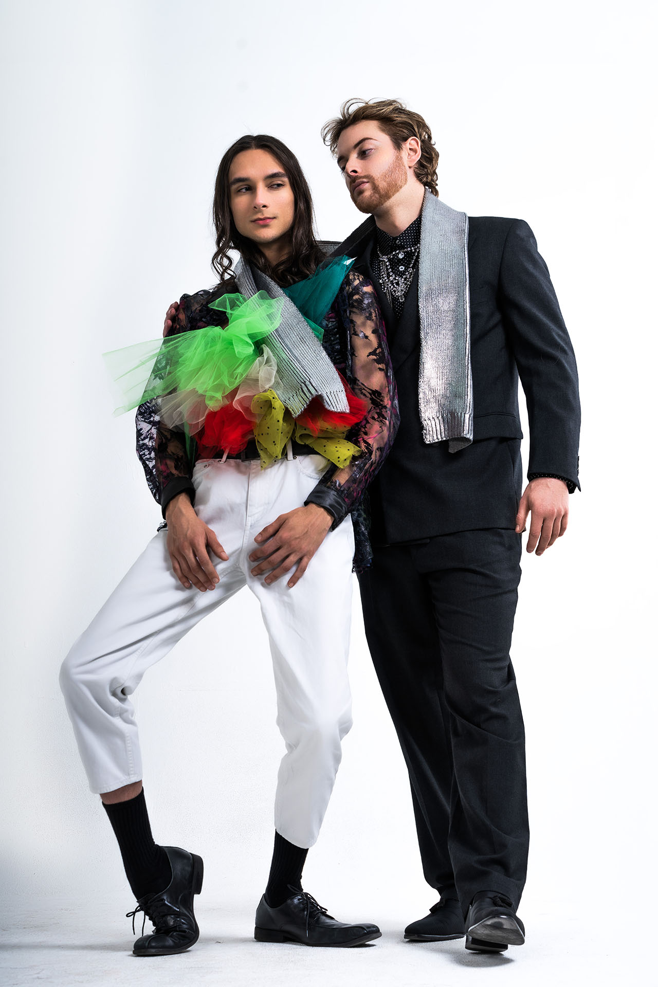 Models in formal Valentine's Day styling, man in a tuxedo and the other wrapped in colorful tulle scarves