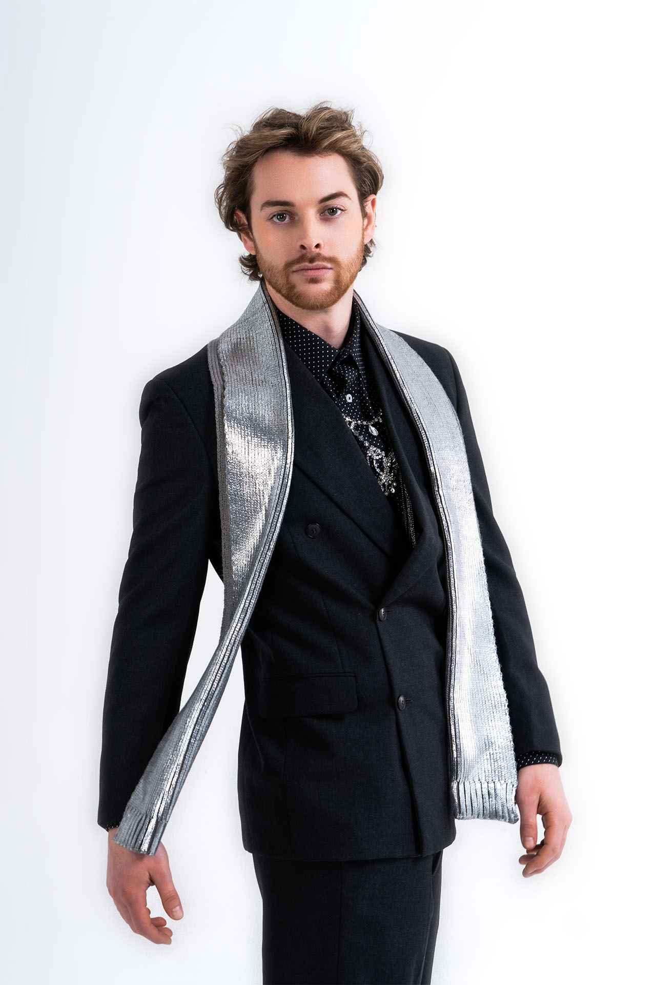 Male model in a black suit with a metallic silver scarf, editorial menswear photography