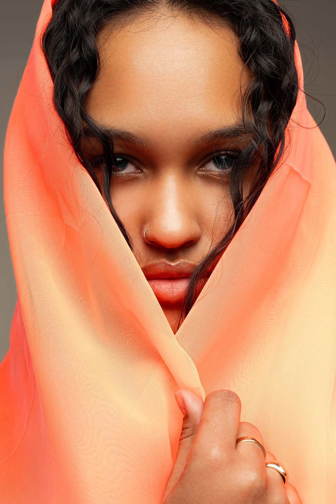 Close-up beauty portrait of a model wrapped in peach-colored fabric, studio lighting