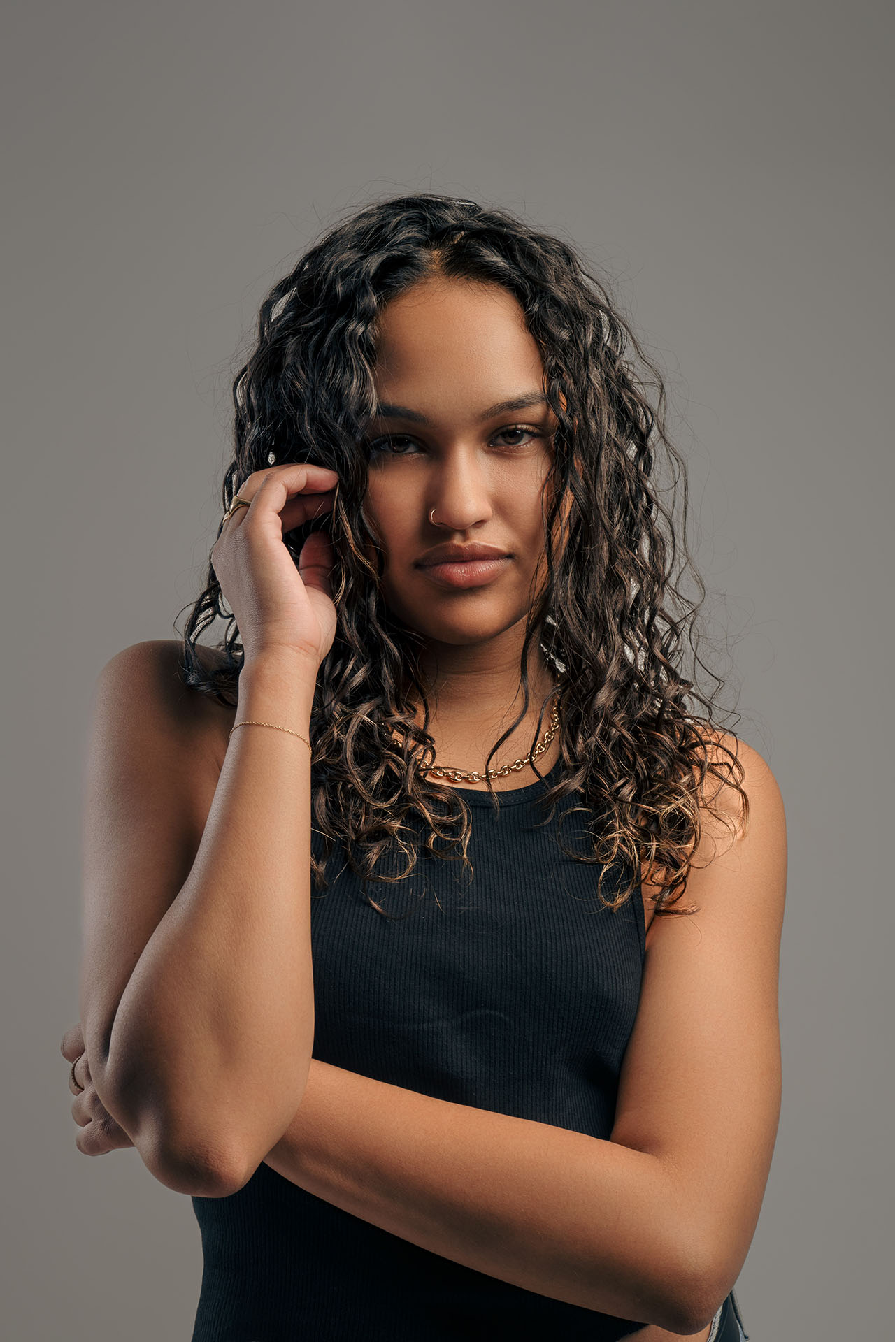 Beauty portrait with hand near the face and dark top, neutral studio background